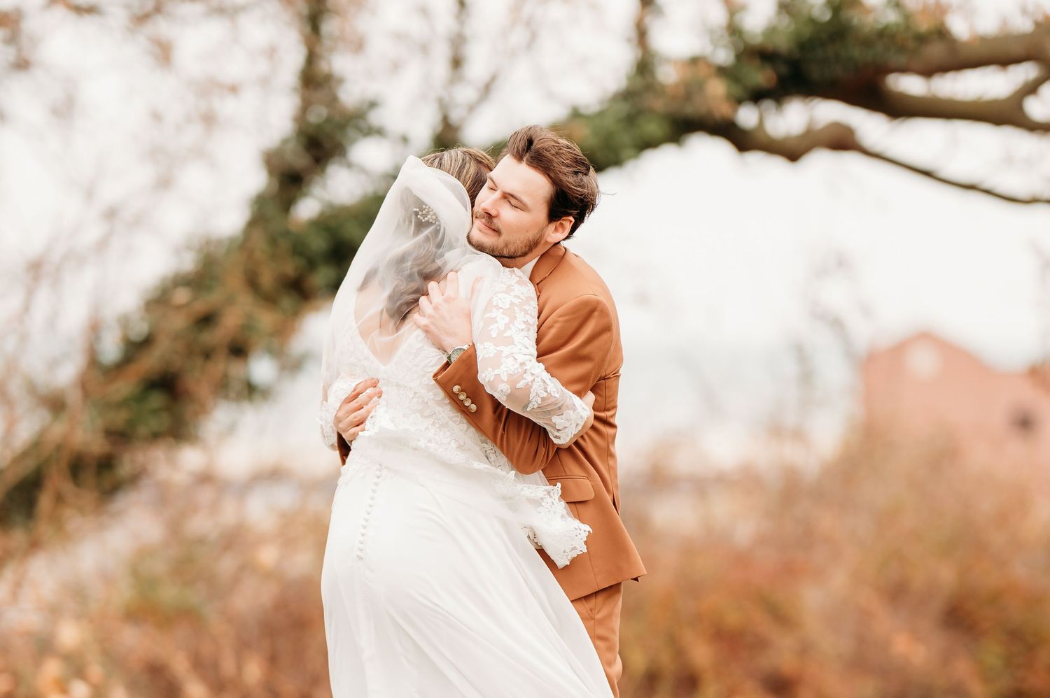 A romantic couple embraces in a dreamy outdoor setting with autumn foliage in the background.