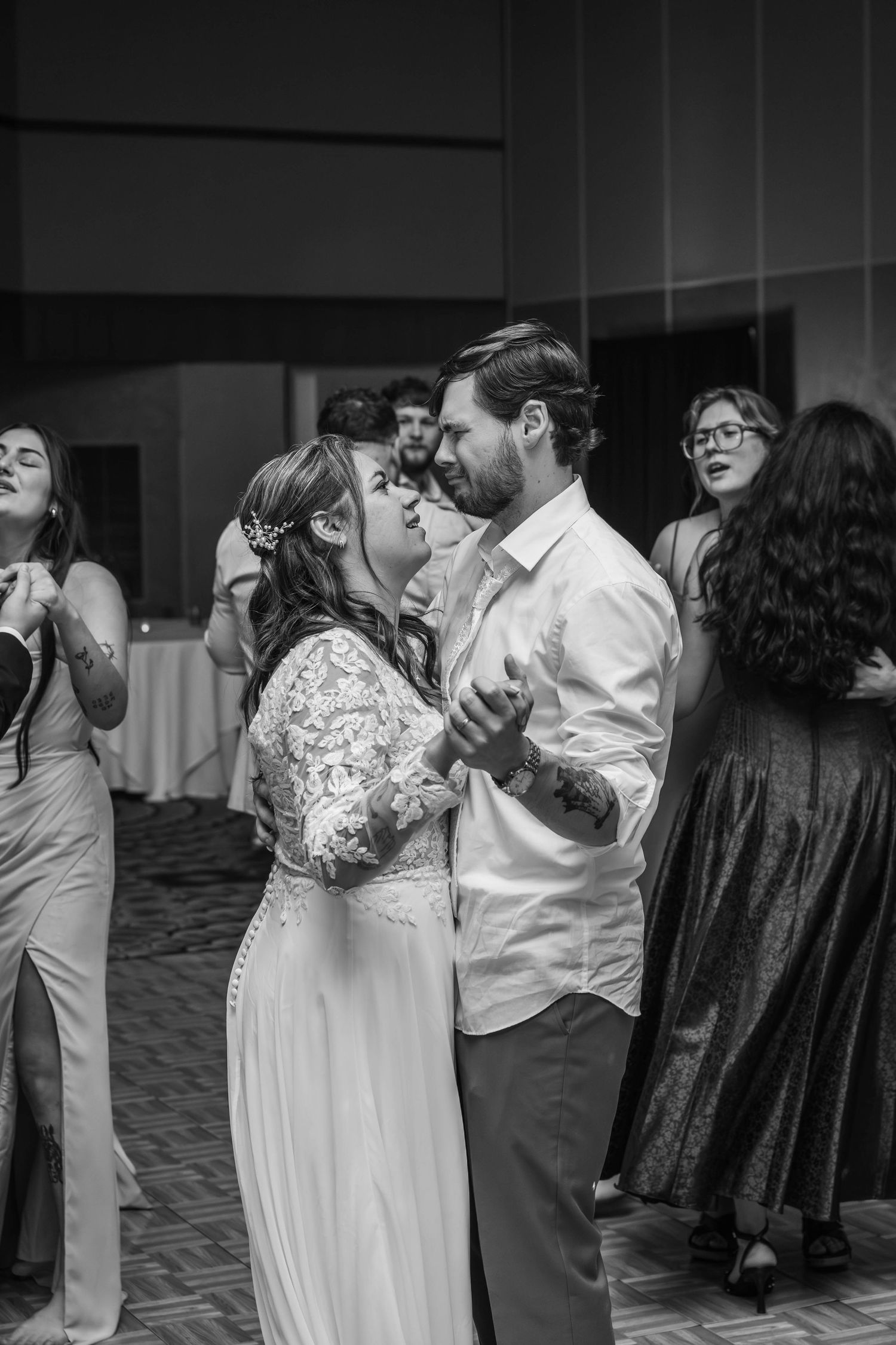 Wedding reception dance floor scene with couples dancing in black and white photography.