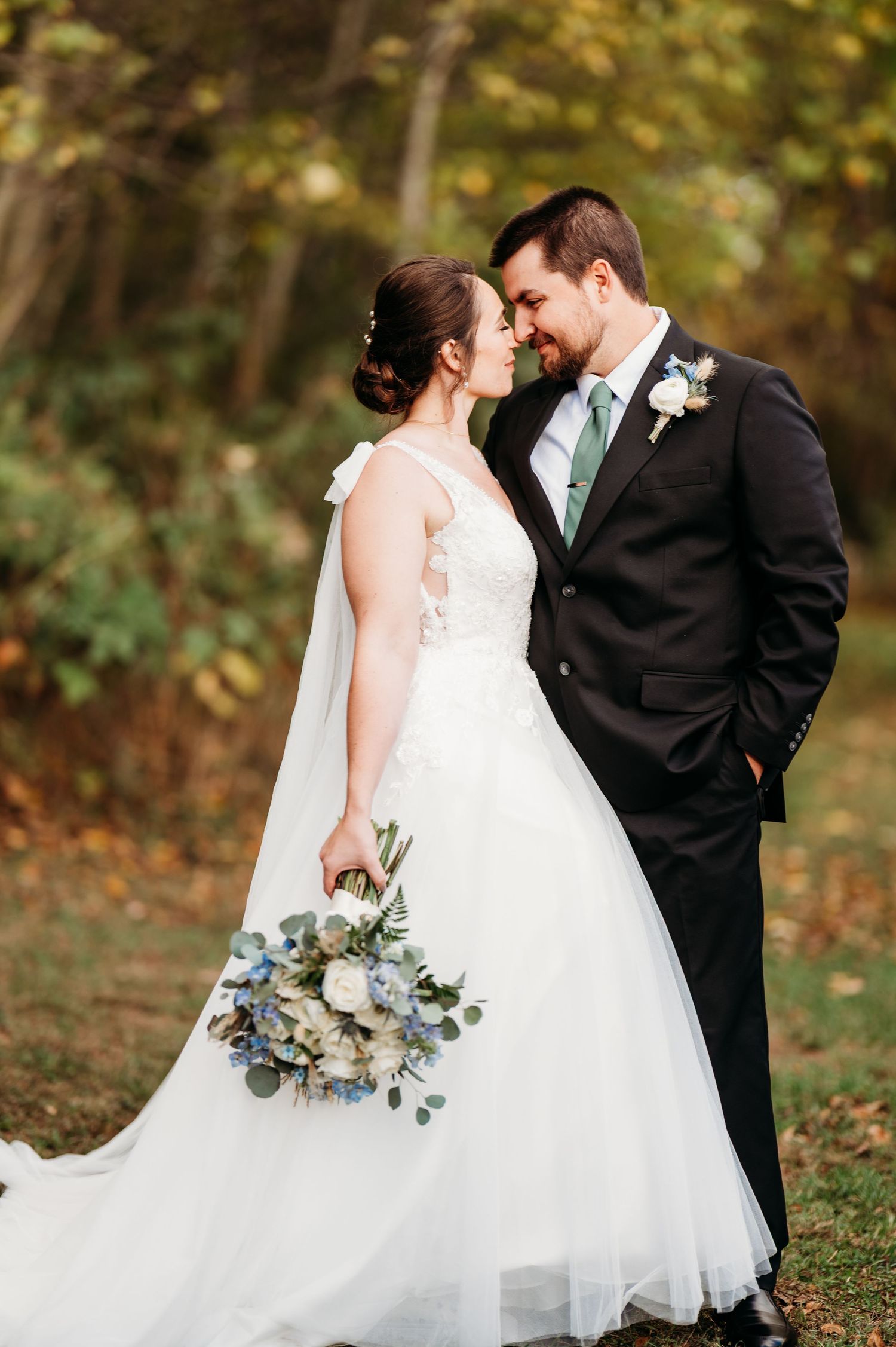 Bride in white gown and groom in black suit share an intimate moment during their fall wedding photoshoot.