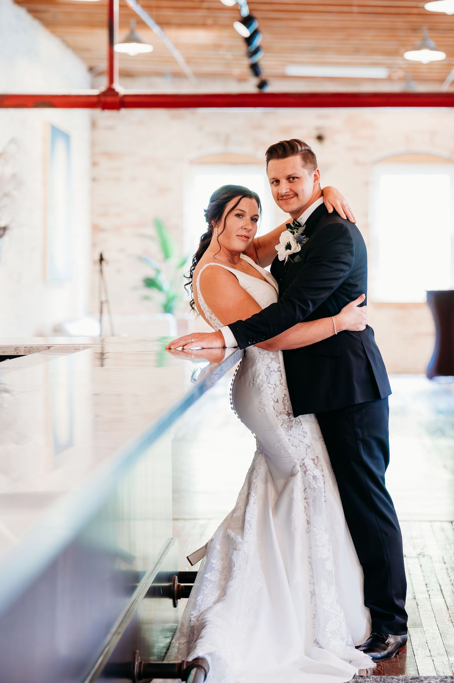 A couple dancing together at their wedding reception, with the bride in white and groom in black suit.