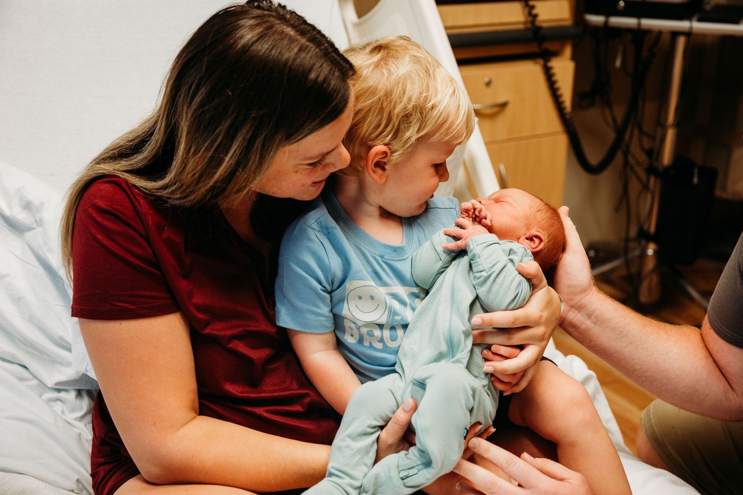 Parents and medical staff tend to a newborn baby in a hospital room setting.