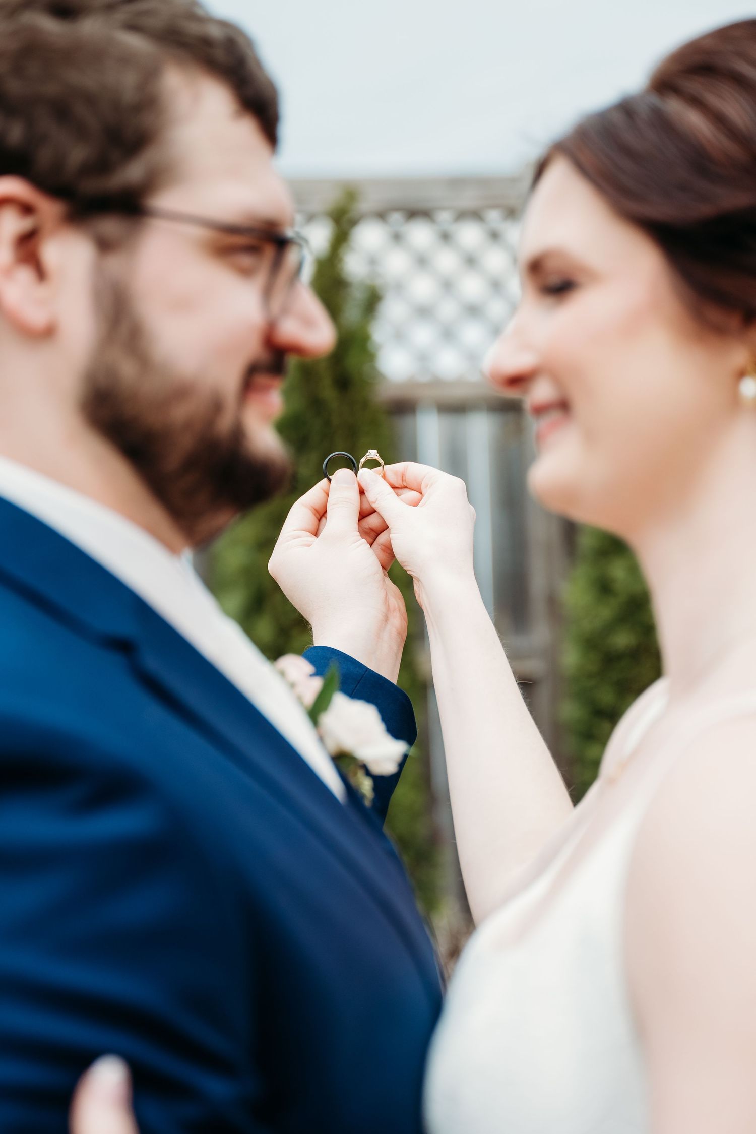 A couple displays their wedding rings while sharing a tender moment during their outdoor wedding celebration.