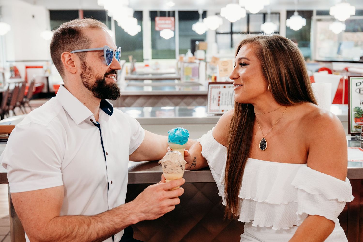 A couple sharing desserts and laughter at a classic American diner counter.