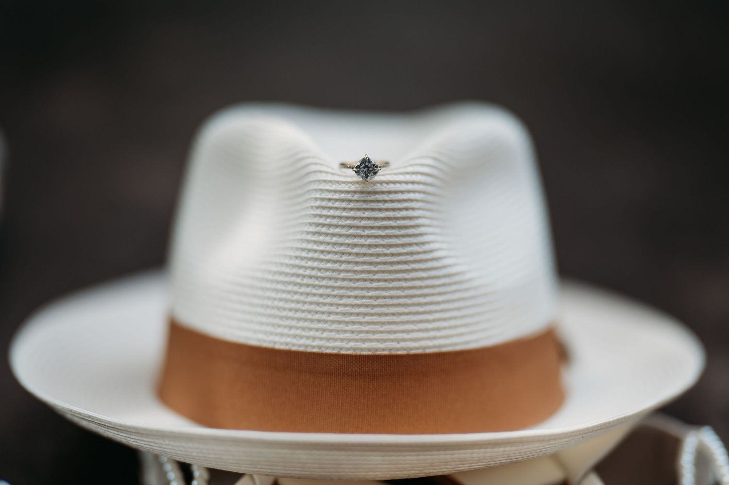 White fedora hat with brown band displayed in multiple angles against dark background.