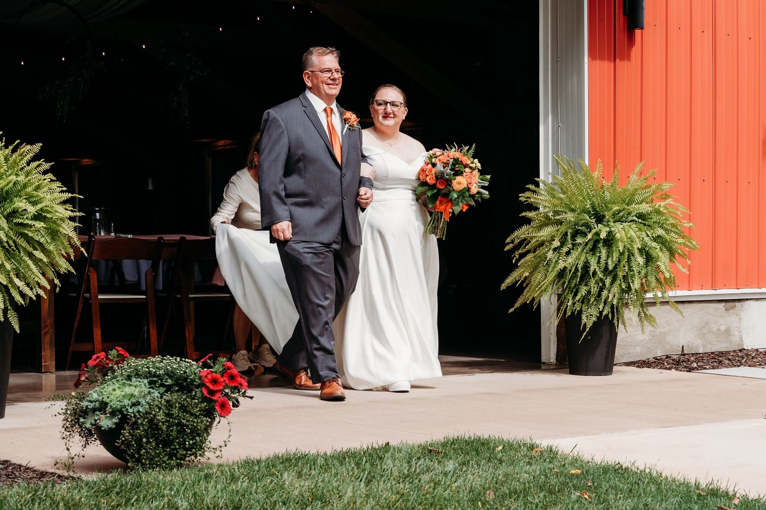 A couple shares romantic wedding photos in front of a rustic red barn on their special day.