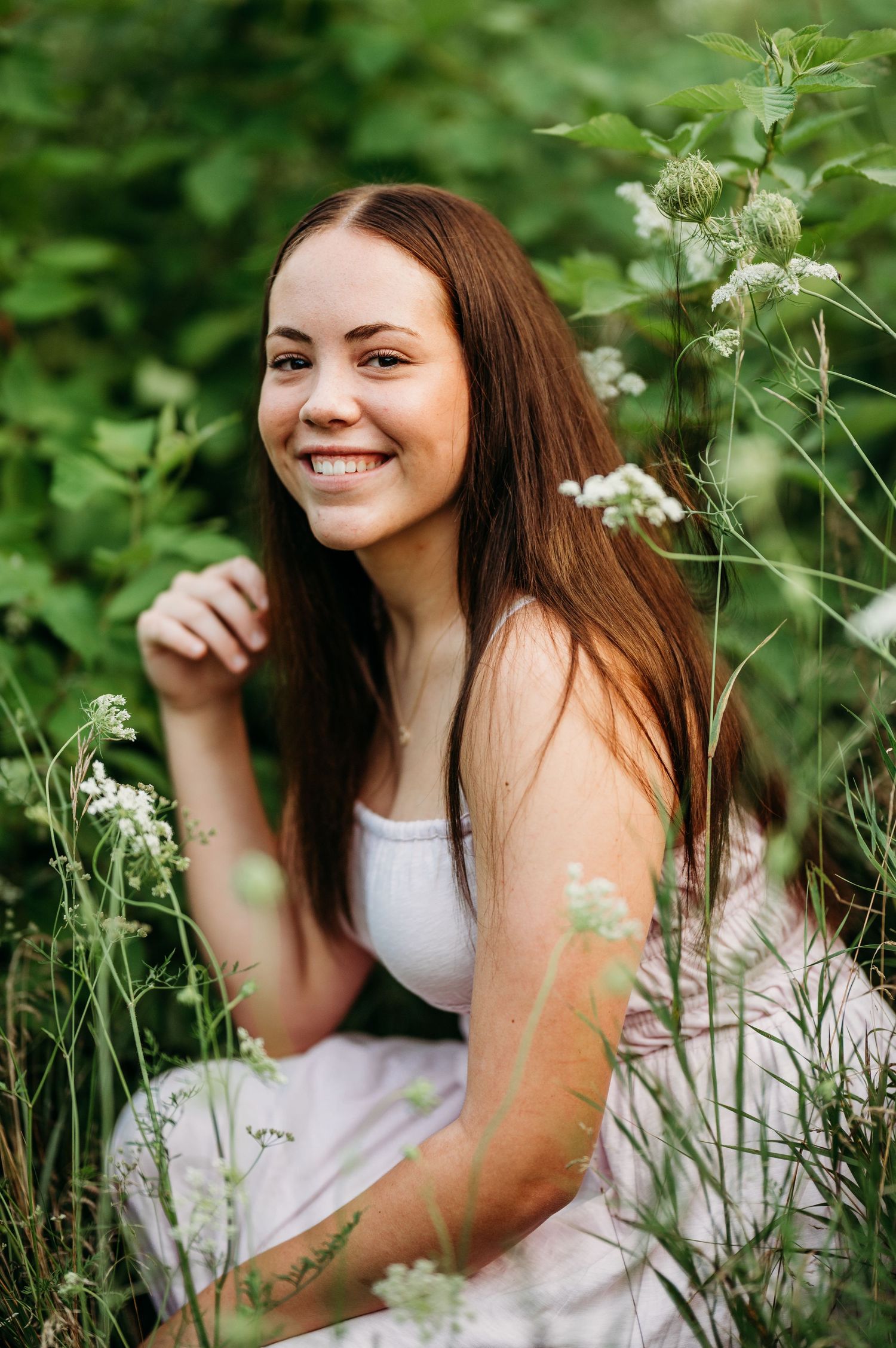 A series of natural outdoor portraits showing genuine expressions among delicate white wildflowers and lush greenery.