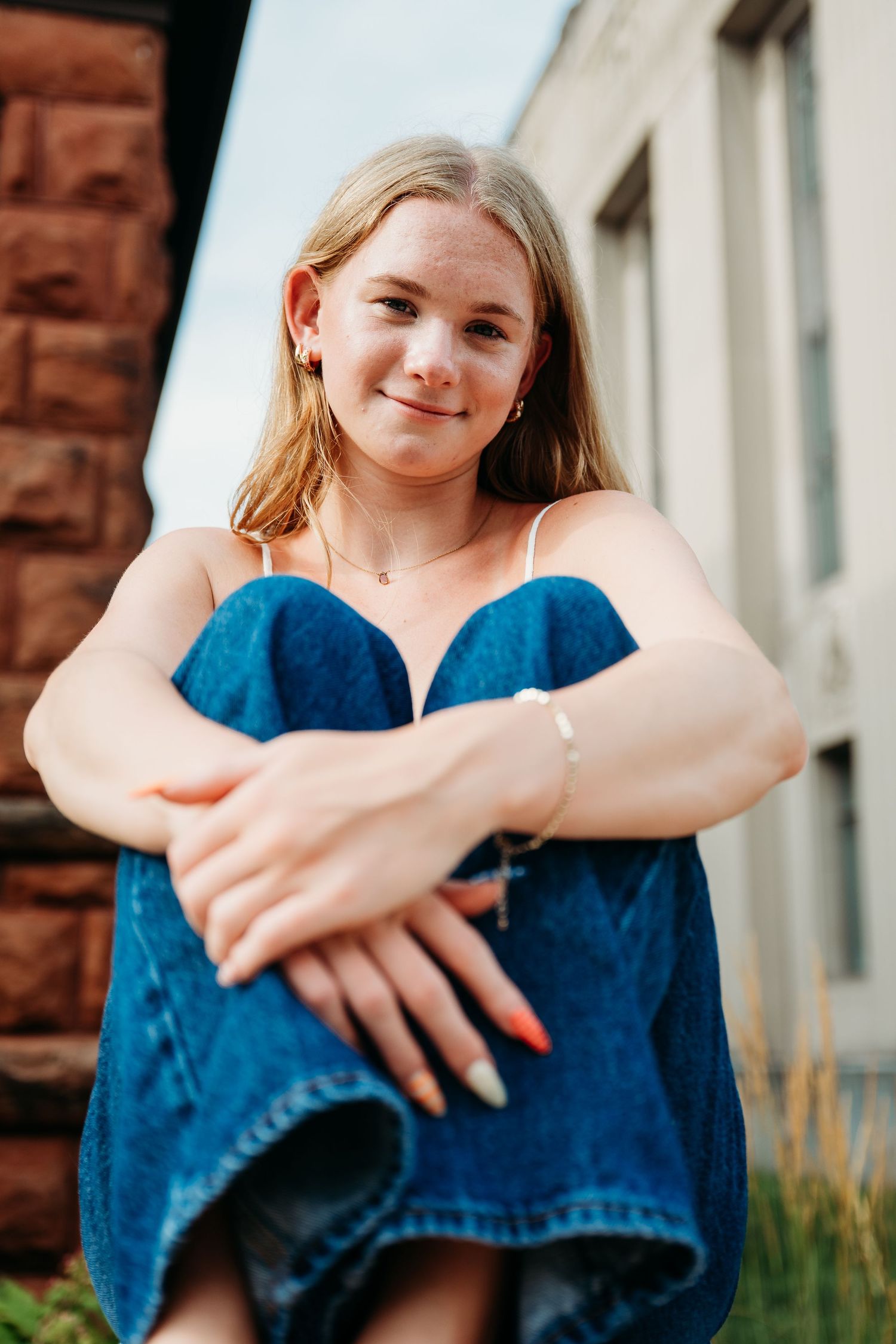 Artistic series of someone sitting in casual denim against a red brick wall backdrop.