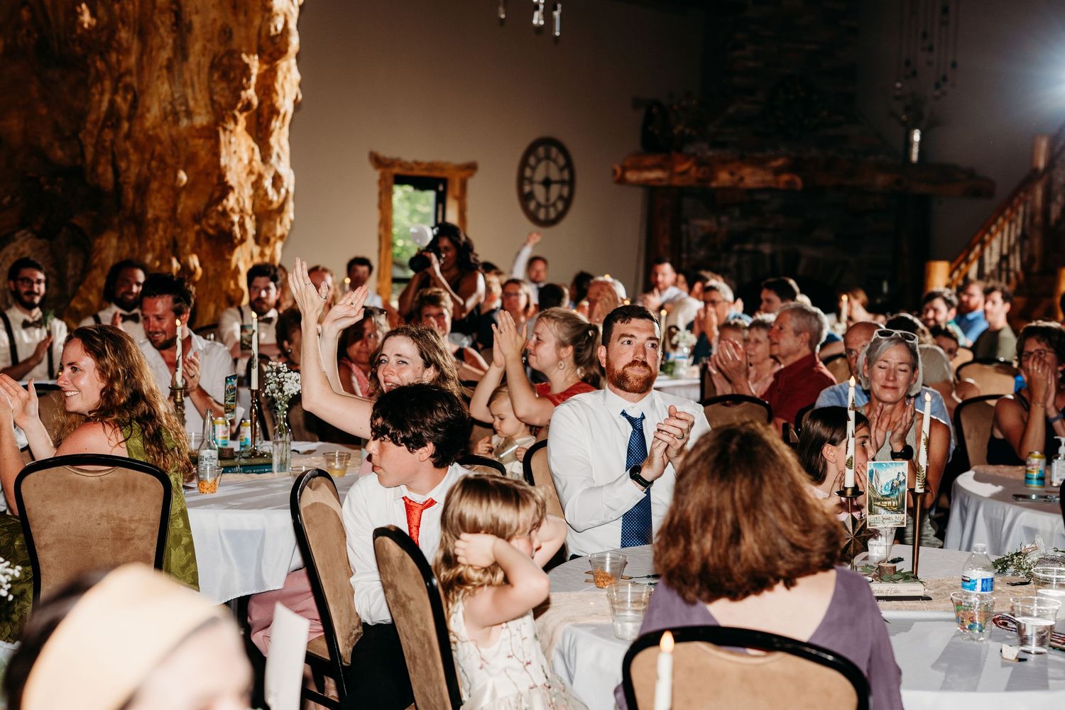 Guests celebrating at a rustic wedding reception in a stone venue with elegant table settings and warm lighting.
