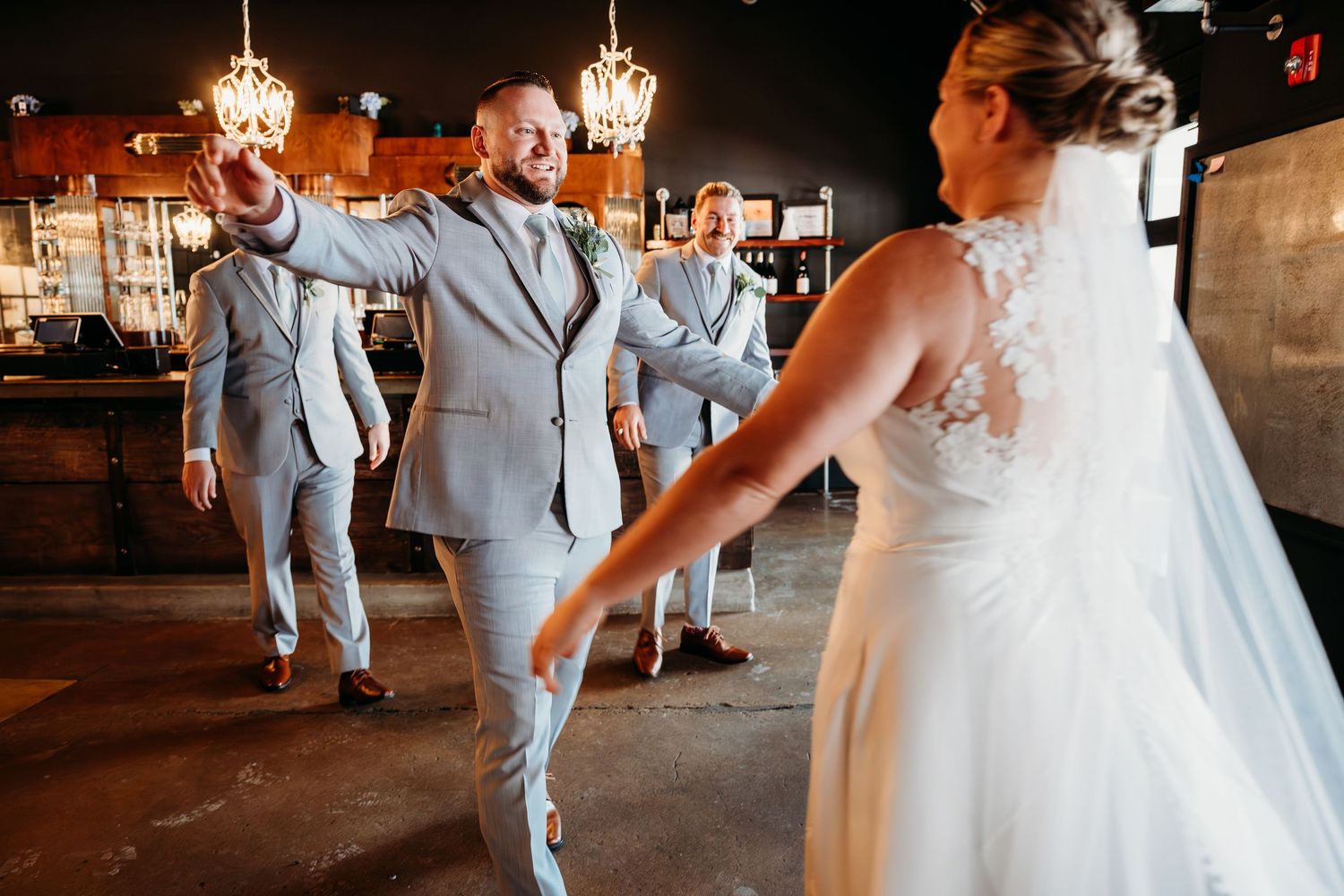Bride and groom share a romantic first dance under elegant chandeliers at their wedding reception.