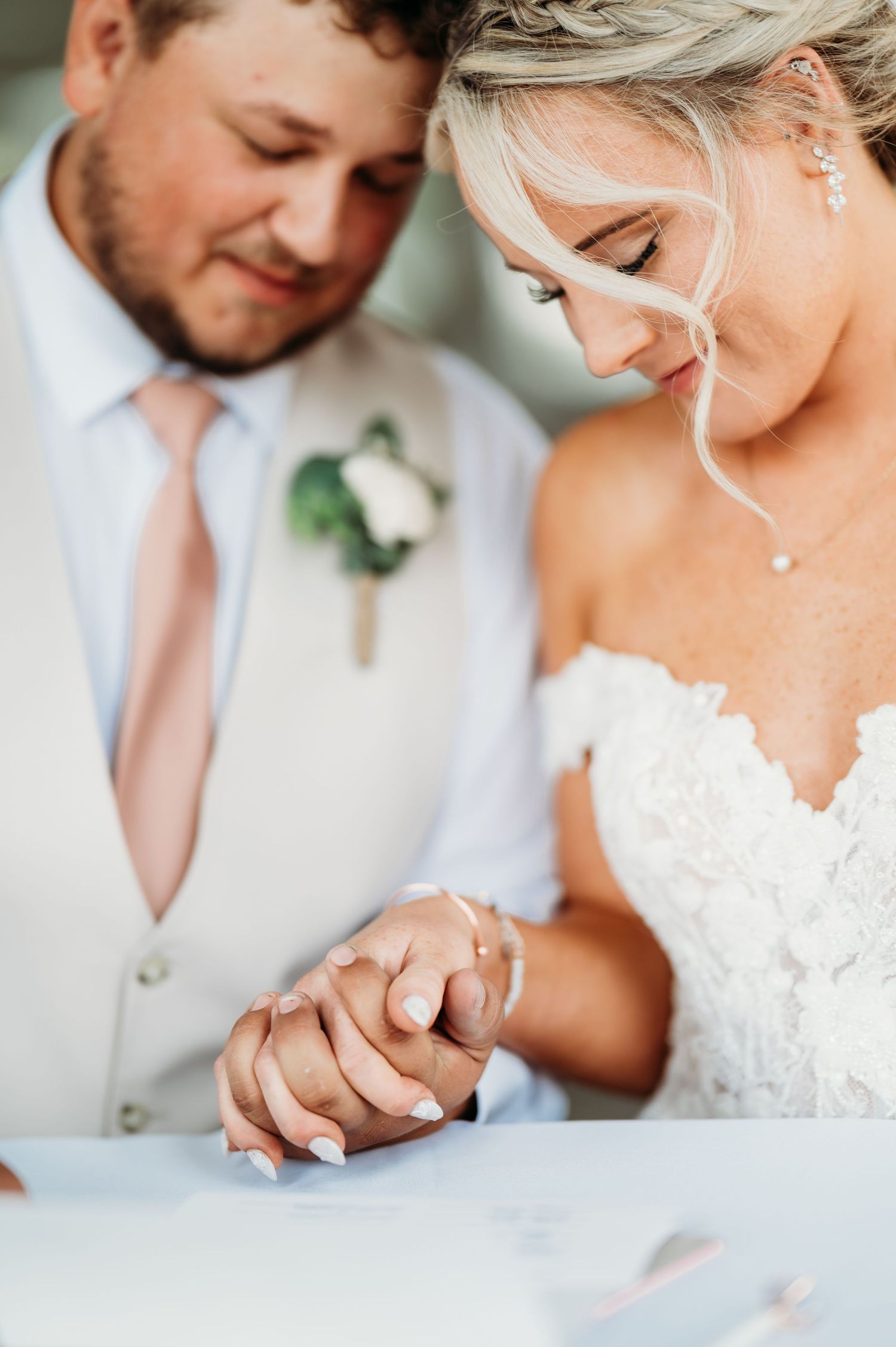 Intimate close-up of couple's hands during tender wedding moment.