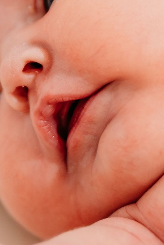 Close-up view of a smiling baby's mouth showing pink lips and smooth skin.