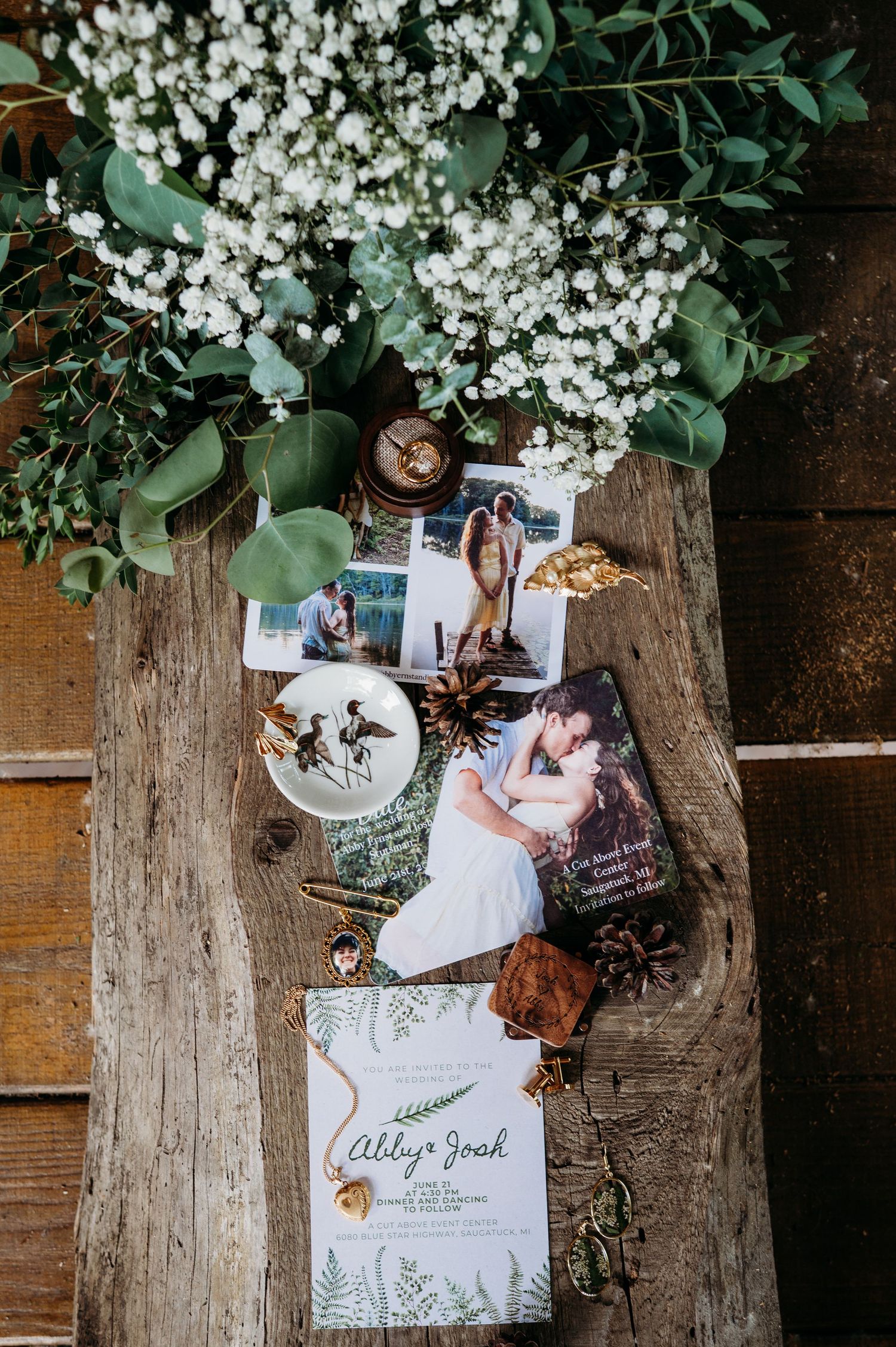 Photos and cards displayed on rustic wooden backdrop with delicate white flowers and green foliage.