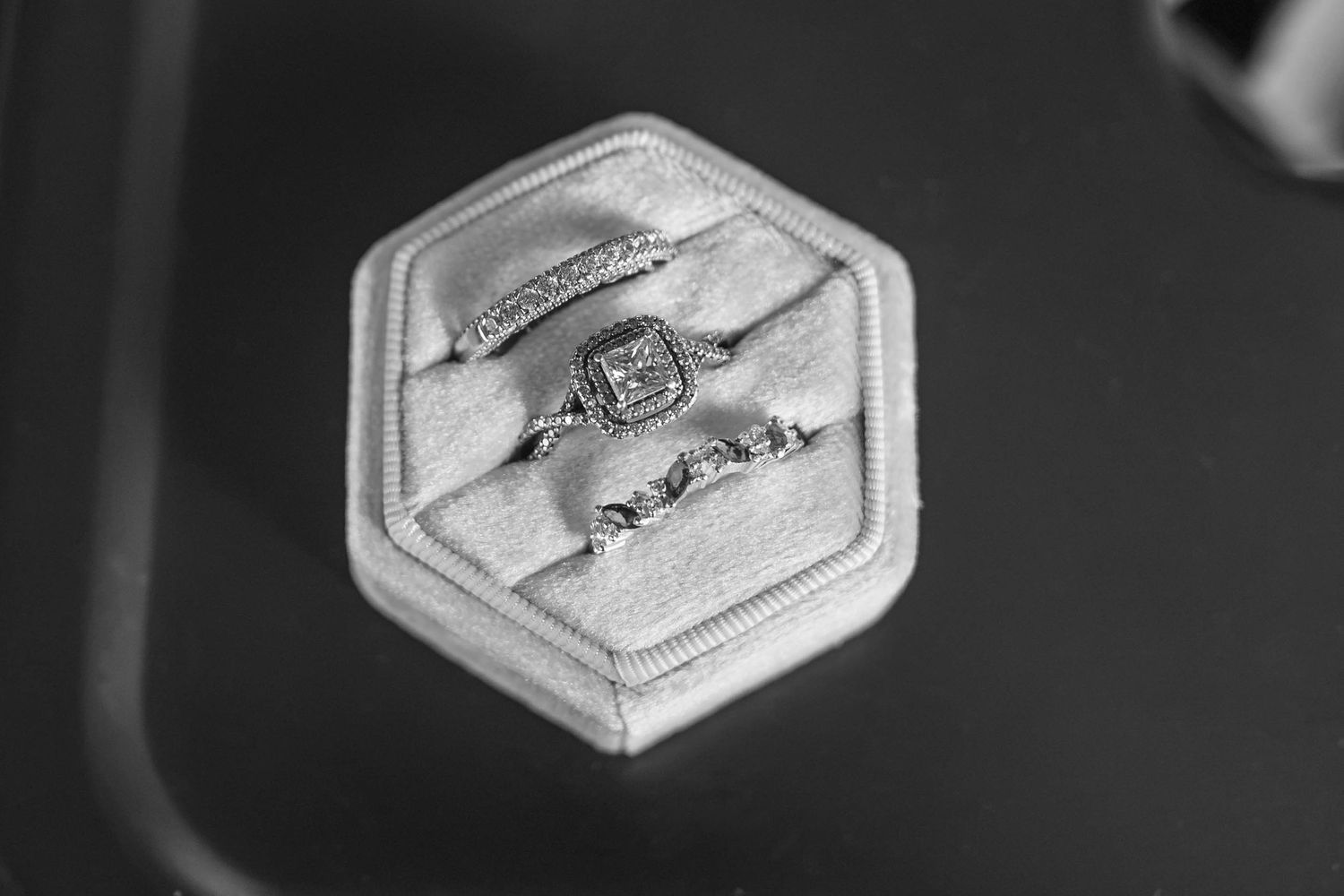 Black and white photo of three diamond rings displayed in a hexagonal velvet ring box.