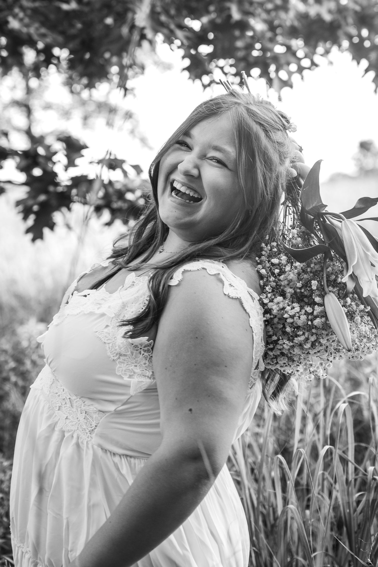 A series of candid black and white portraits showing a person in a white dress twirling joyfully in a garden.