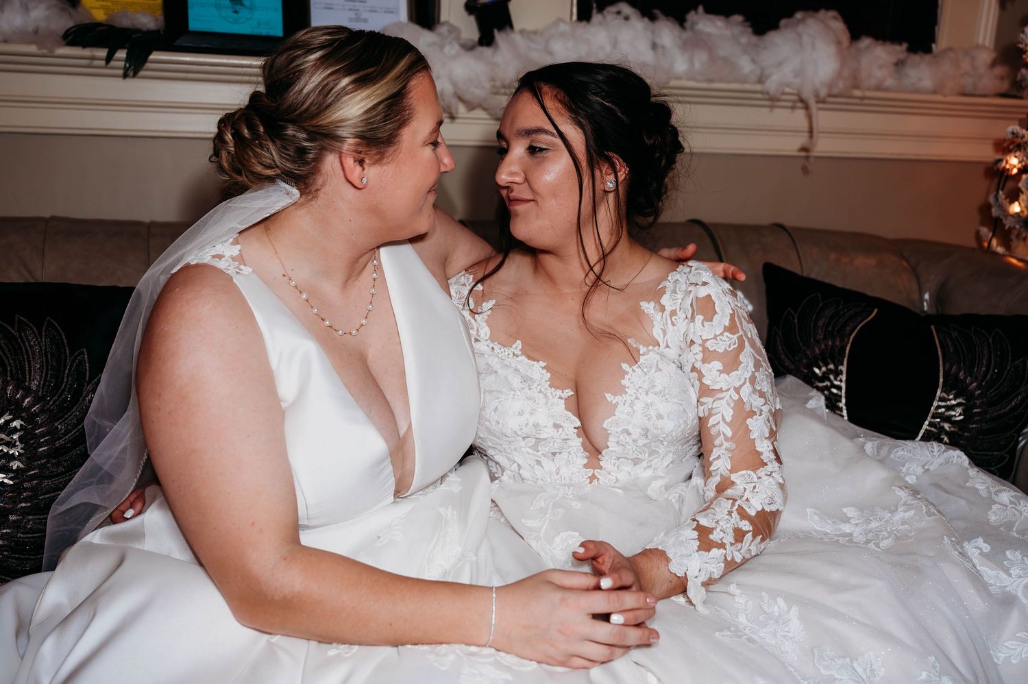 Two people in elegant white wedding dresses share an intimate moment together during their celebration.