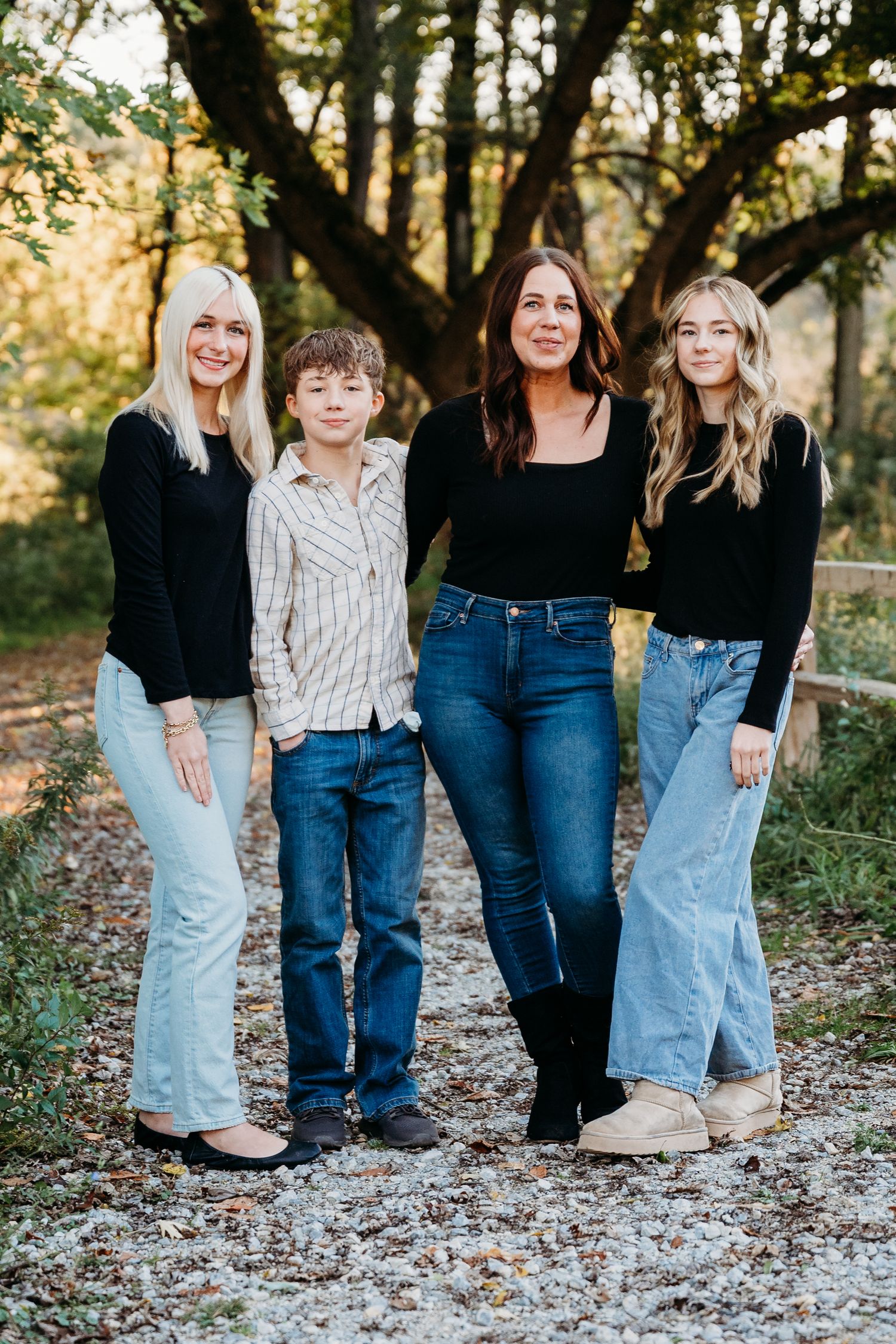 A group in coordinated denim and casual wear poses together on a leaf-covered path in an autumn outdoor setting.