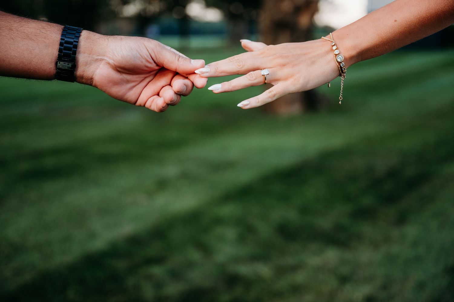 Close-up shot of hands passing a wooden popsicle stick against a blurred green background.
