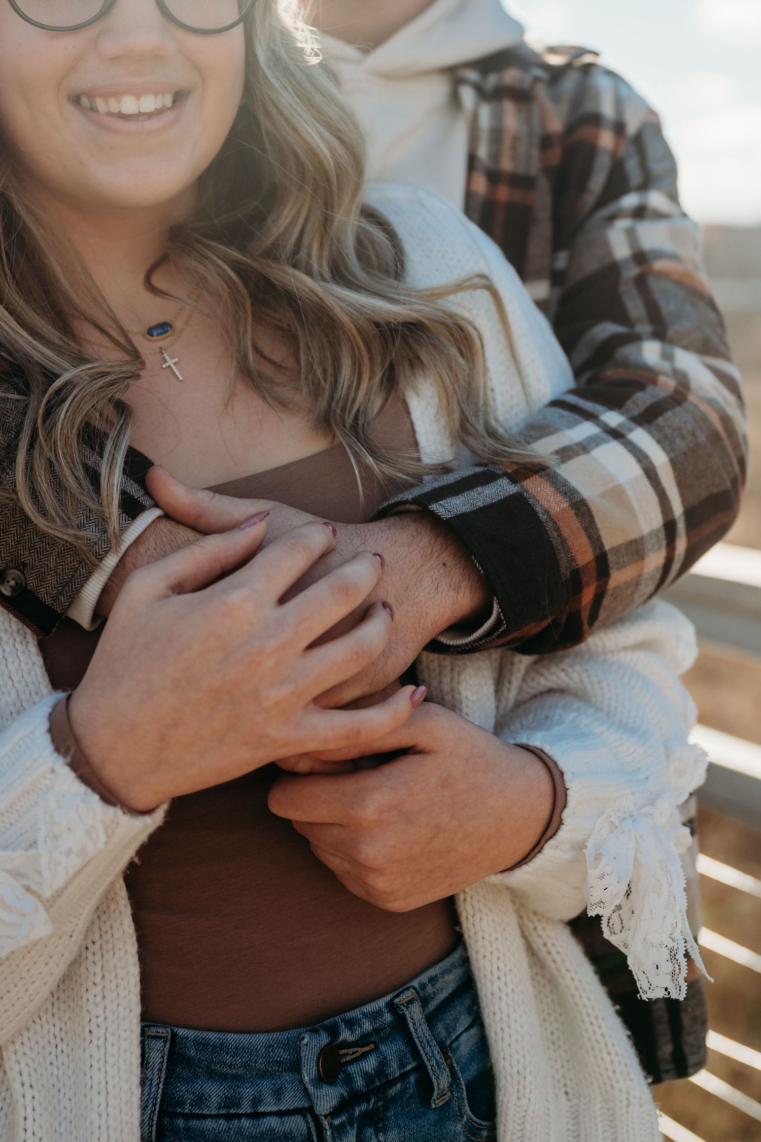 Close-up sequence showing someone wearing a white knit sweater and denim being embraced in a tender moment.