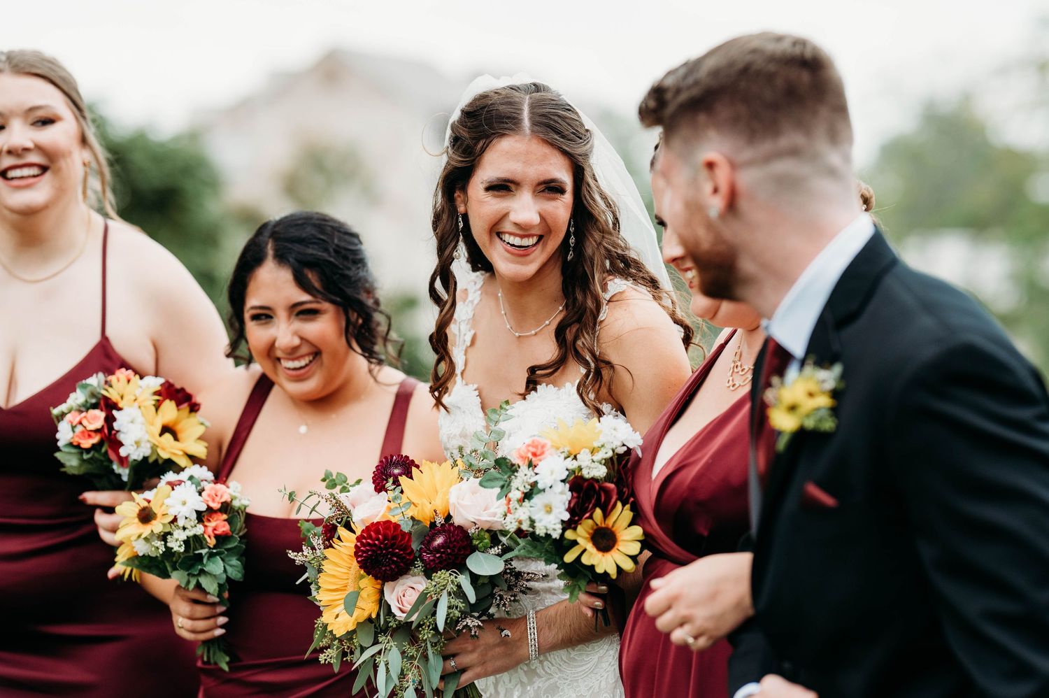Candid moments from a wedding party in burgundy and black attire holding vibrant autumn-colored bouquets.