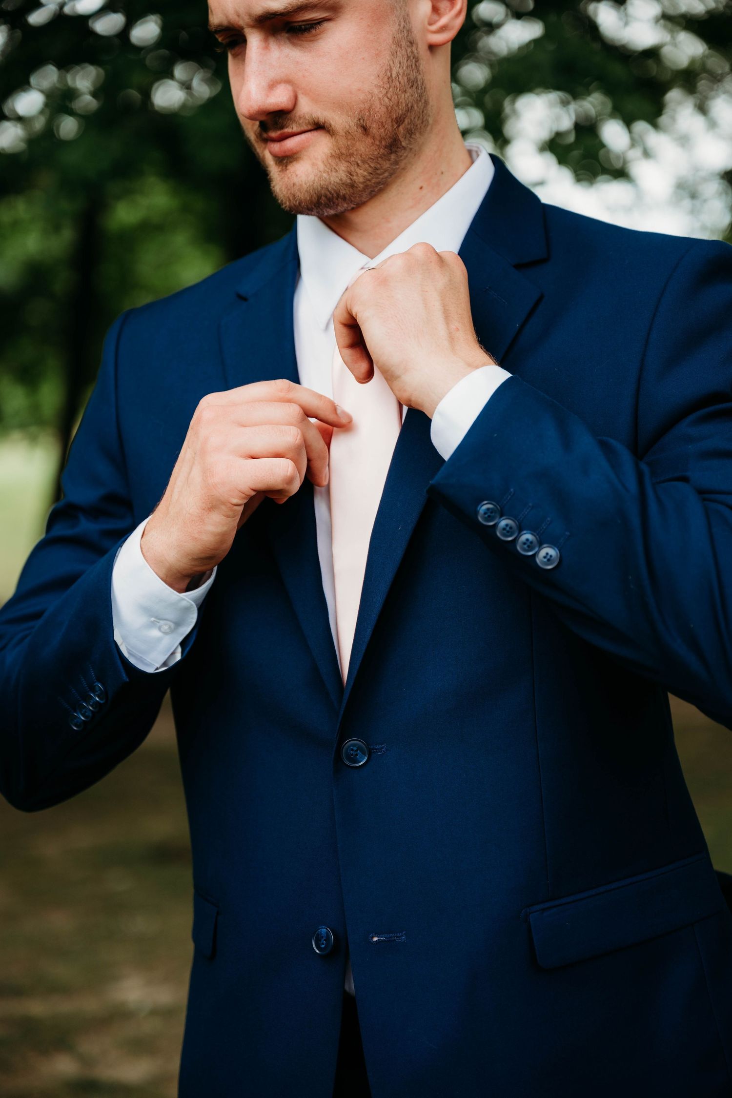 A series of close-up shots showing a man in a navy suit adjusting his tie with a thoughtful expression.