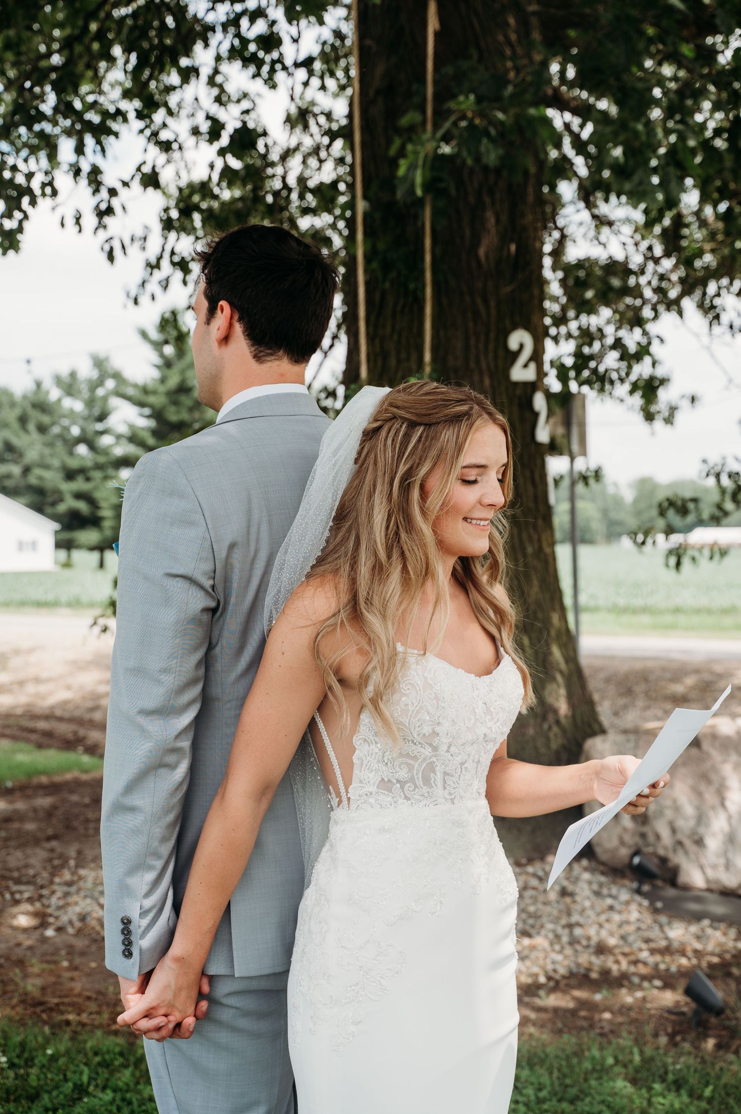 A couple shares a private first look moment before their wedding ceremony under a large tree.