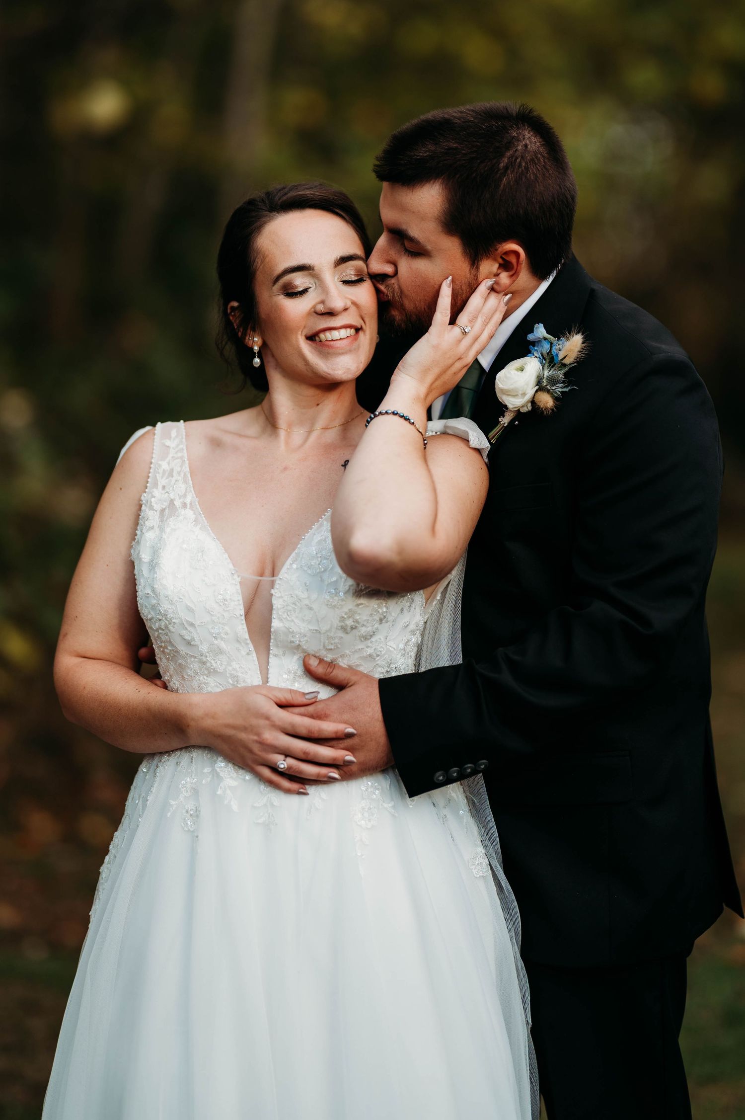 A romantic wedding couple embraces outdoors during an autumn photo session in a natural setting.