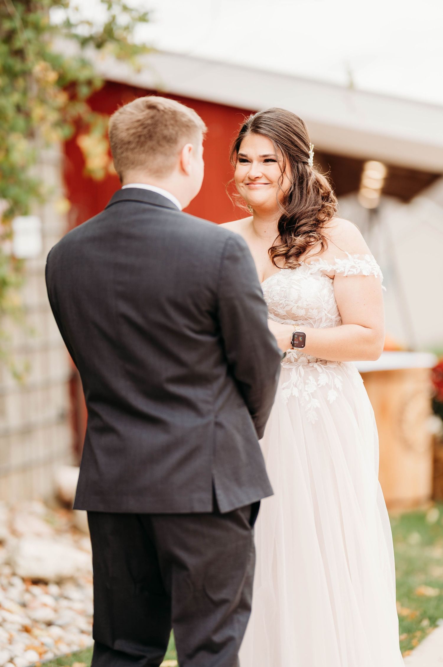 A couple shares their first look moment outside a red barn during an autumn wedding.