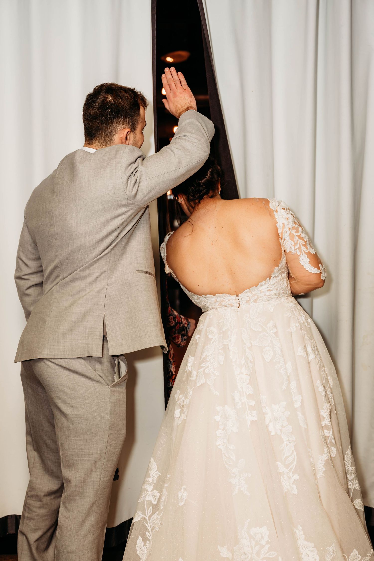 Wedding party members in gray suits and white dresses dancing together at a reception.
