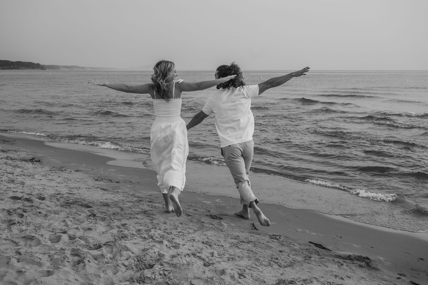 Black and white photograph of a couple embracing and sharing intimate moments on a beach.