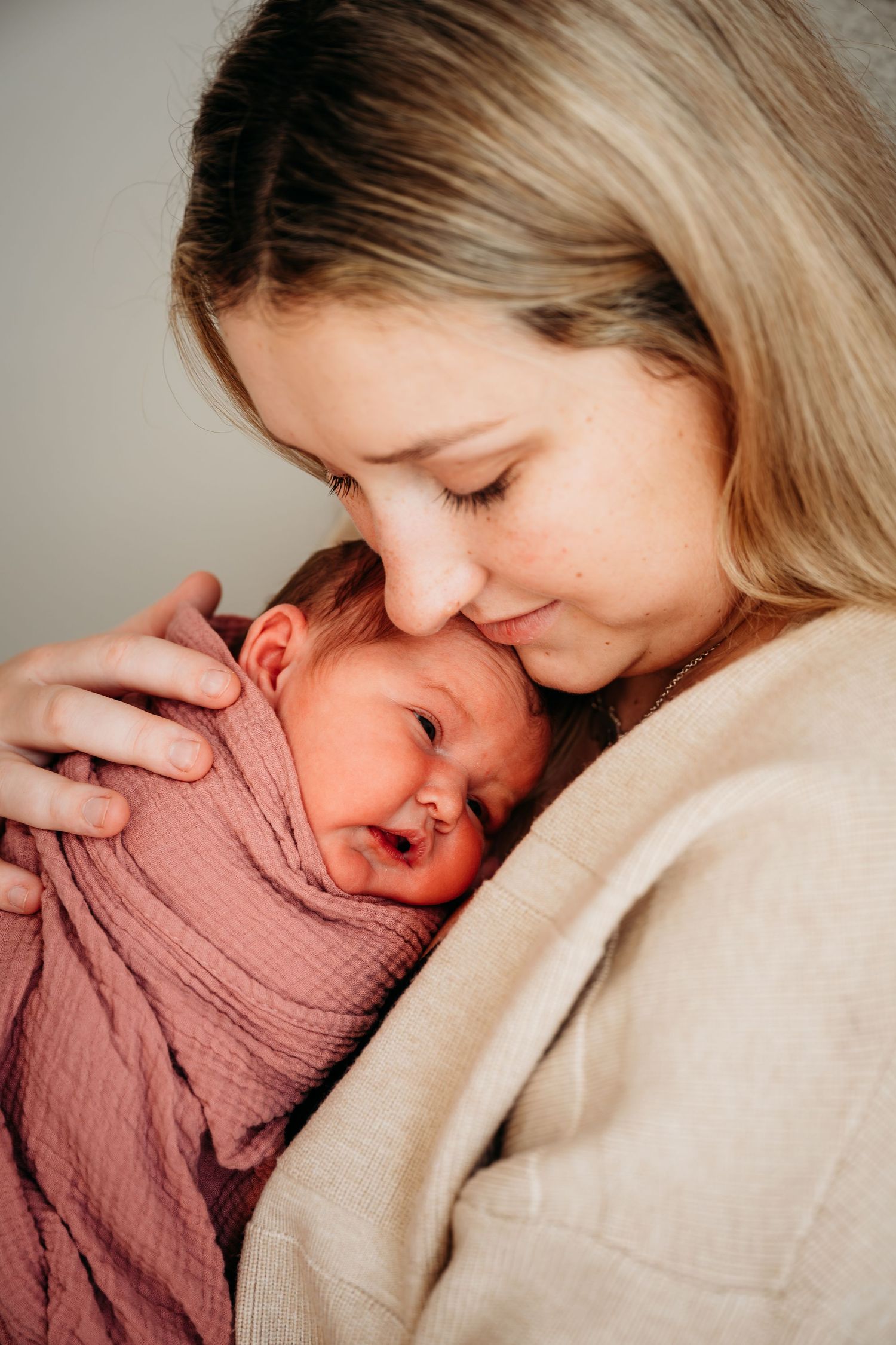 A tender moment captured in a series of four intimate photos showing a parent cradling and bonding with a newborn baby.