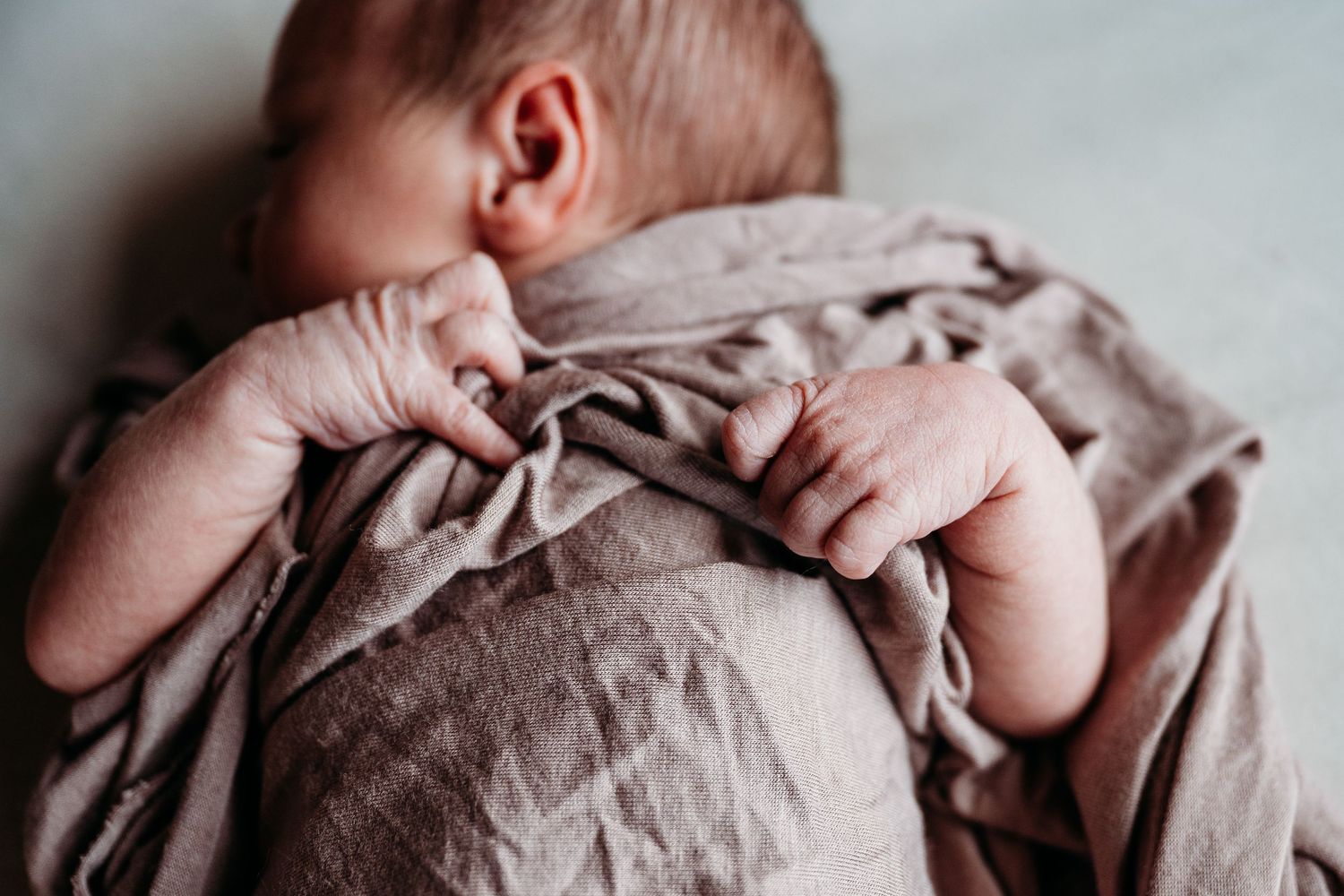 A series of black and white close-up photographs showing gentle hands cradling and comforting a newborn baby.