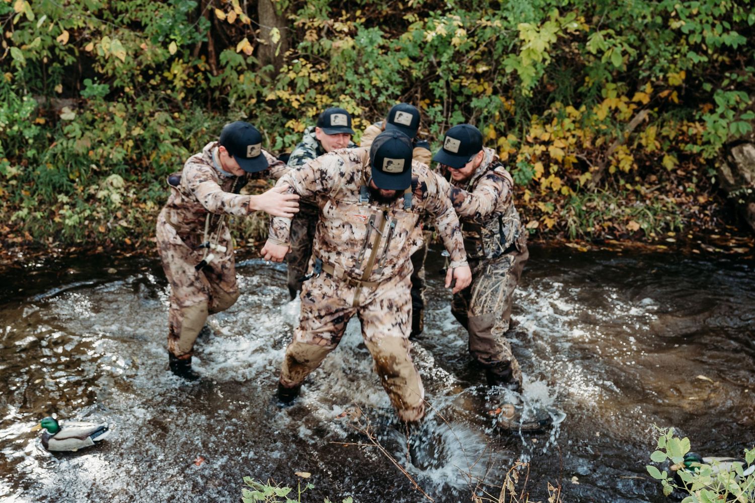 Soldiers in desert camouflage uniforms splash through a stream during a training exercise.