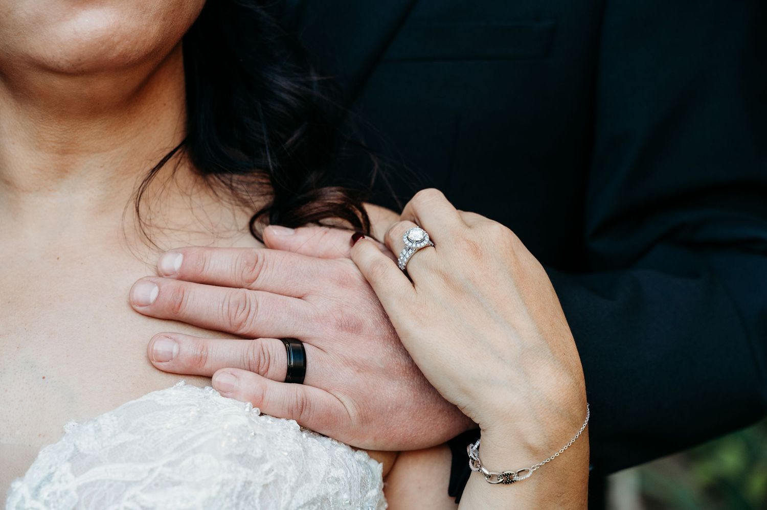 Close-up of hands with wedding rings and a white dress, showing an intimate moment between newlyweds.