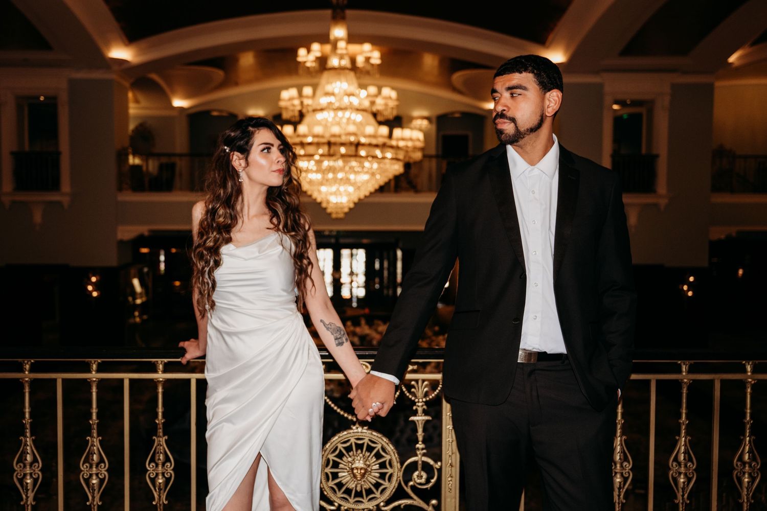 A bride and groom share their first dance under elegant crystal chandeliers in a grand ballroom.