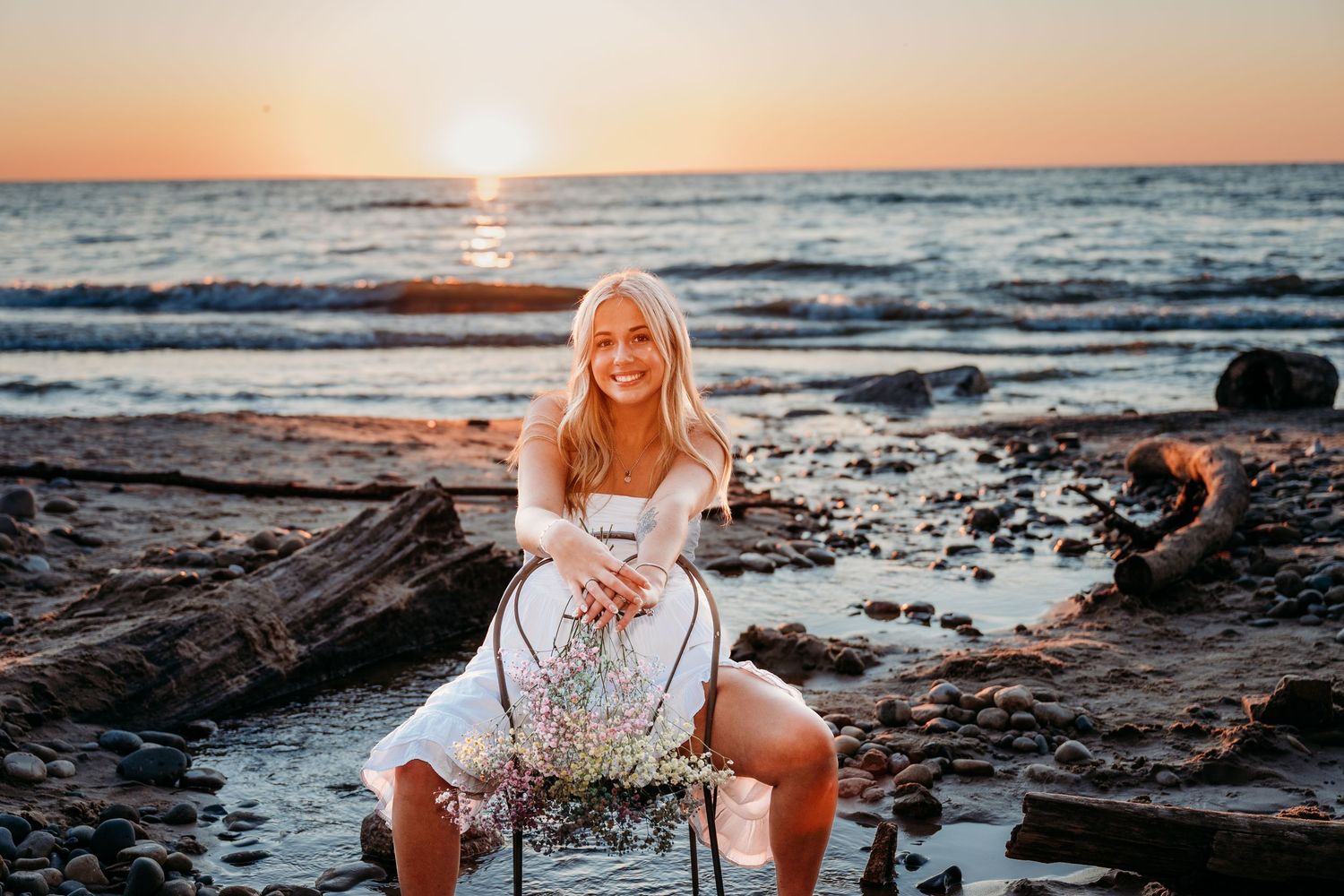 Person in white dress poses by ocean shore during sunset in a series of connected beach photos.