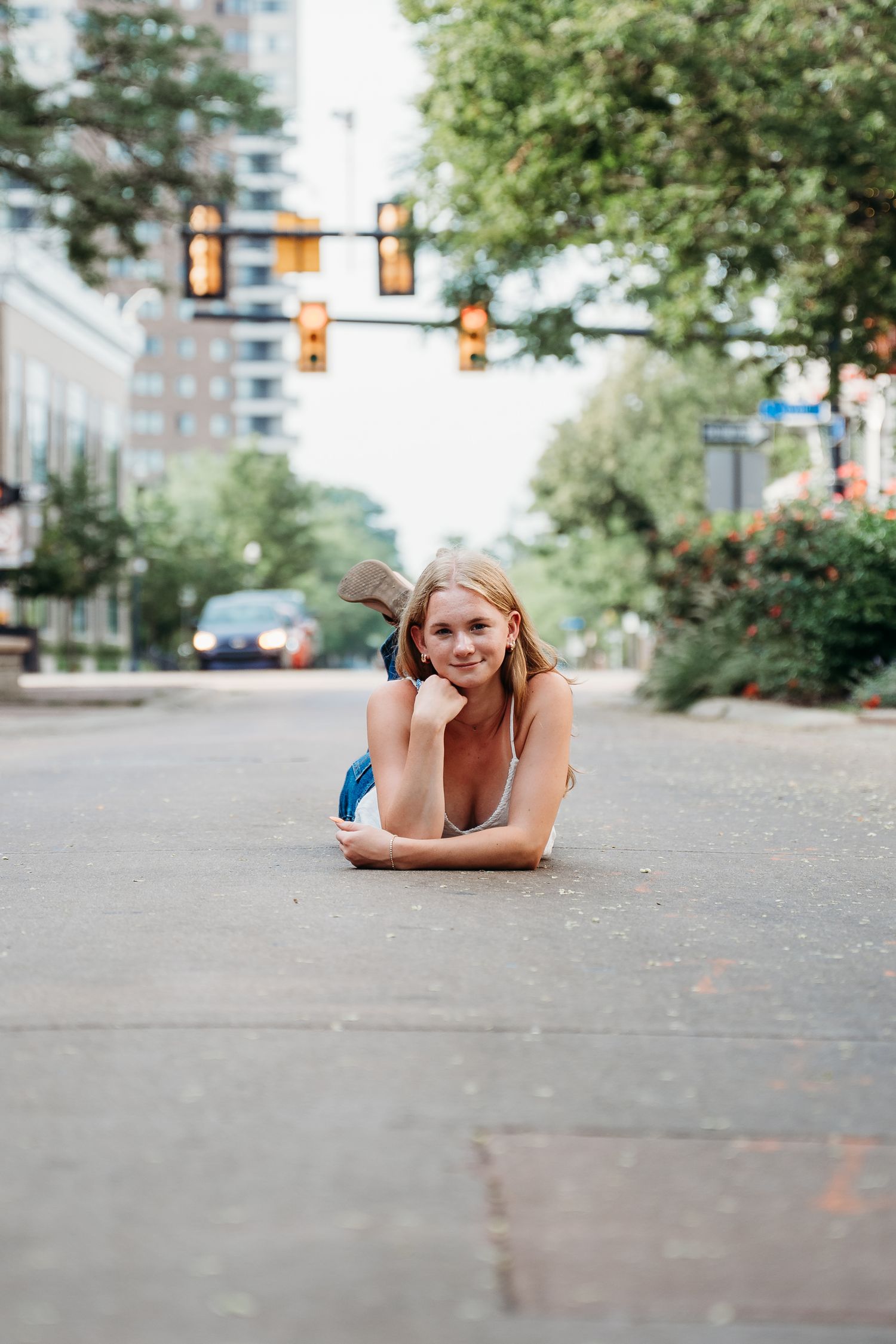 A series of photos showing someone lying on a concrete sidewalk with traffic signals and trees in the urban background.