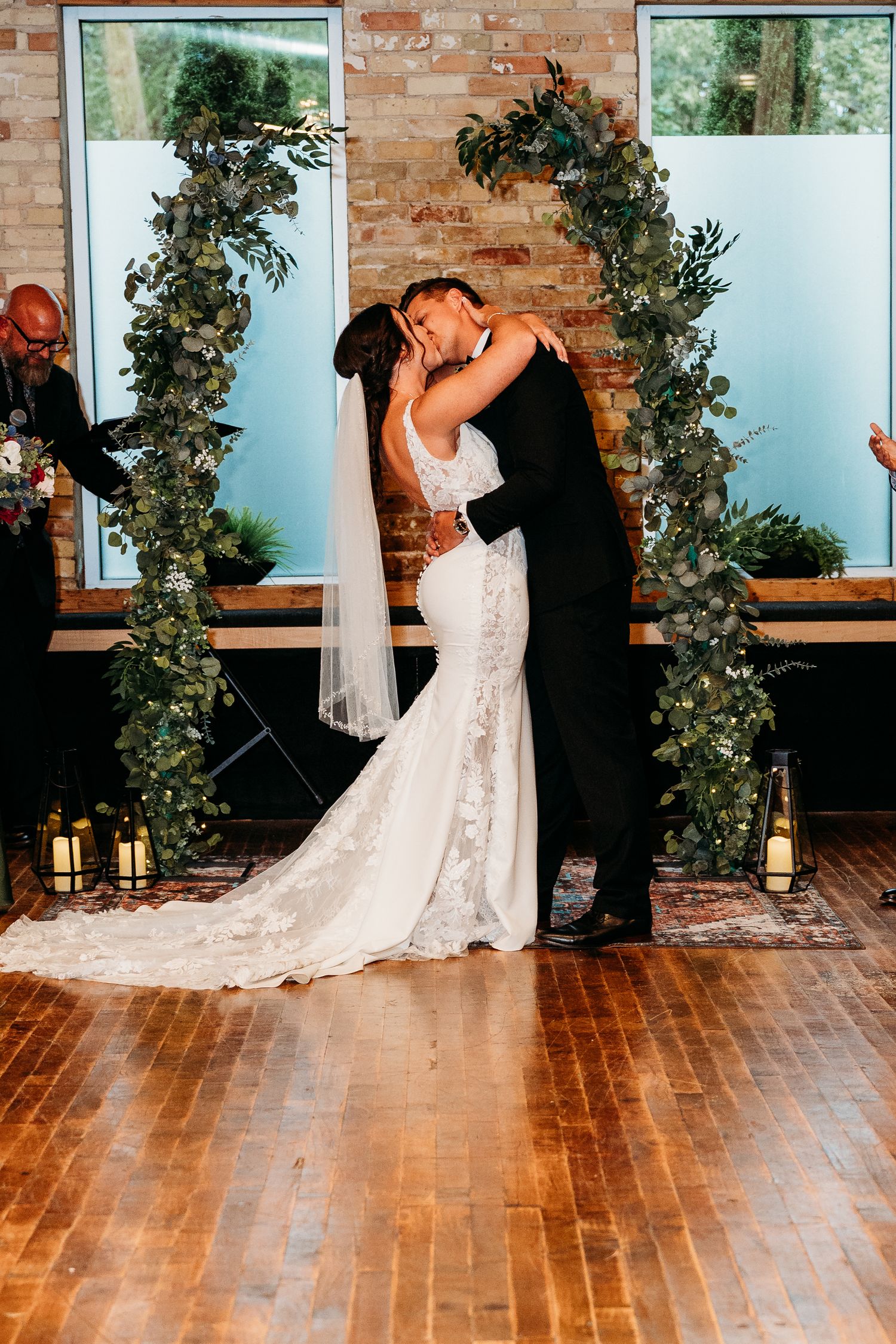 A sequence of romantic wedding photos showing a couple dancing in front of a brick wall with greenery arches.