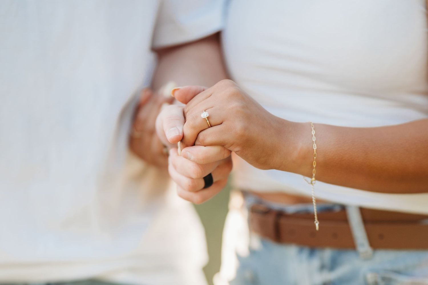 A person's hands hold a white wedding dress fabric, adjusting and smoothing the delicate material.