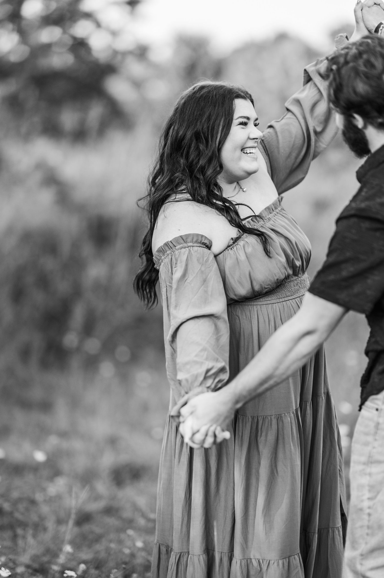 A couple in a romantic embrace share a joyful moment together outdoors in black and white photography.