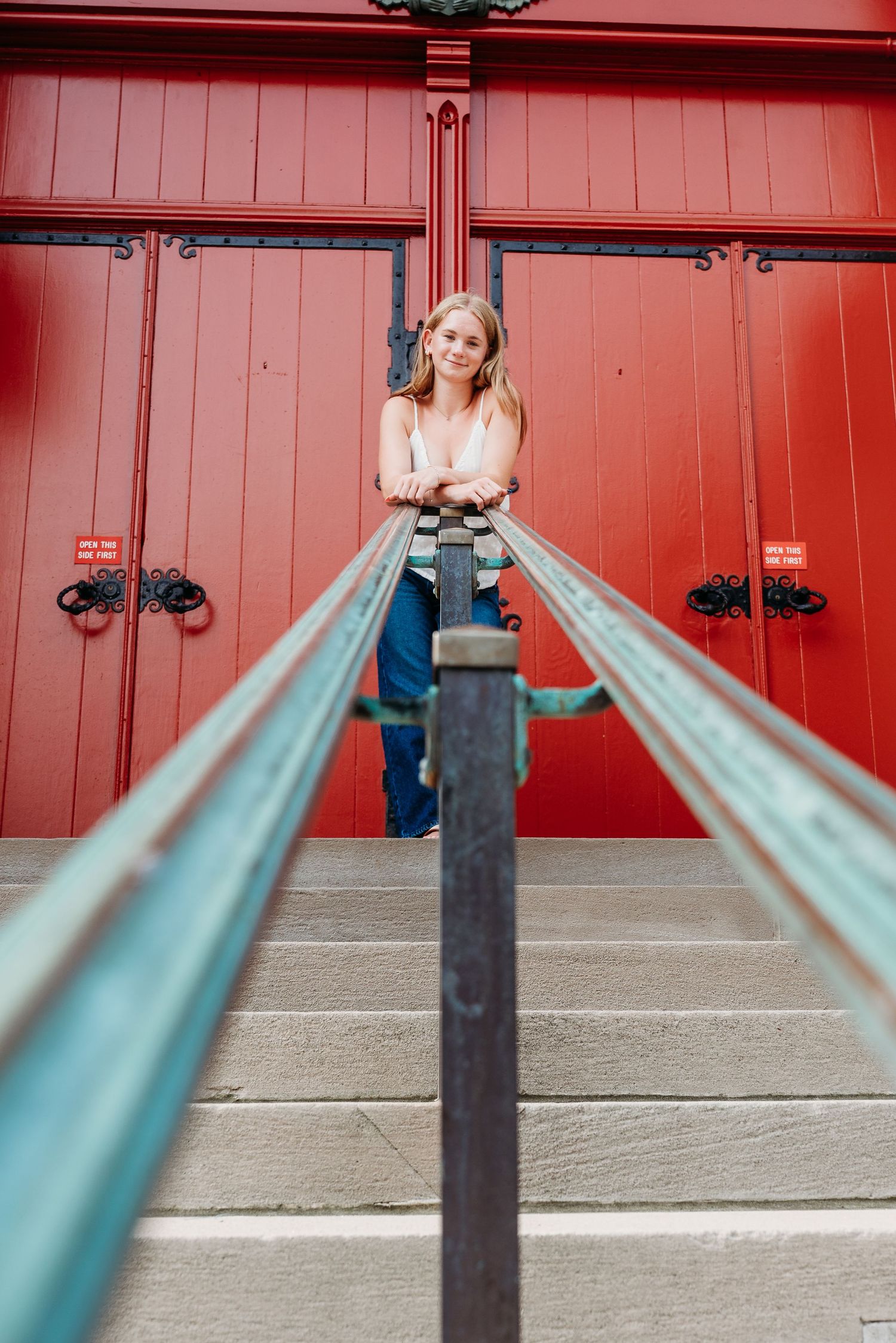 Architectural detail of turquoise railings against red wooden doors.