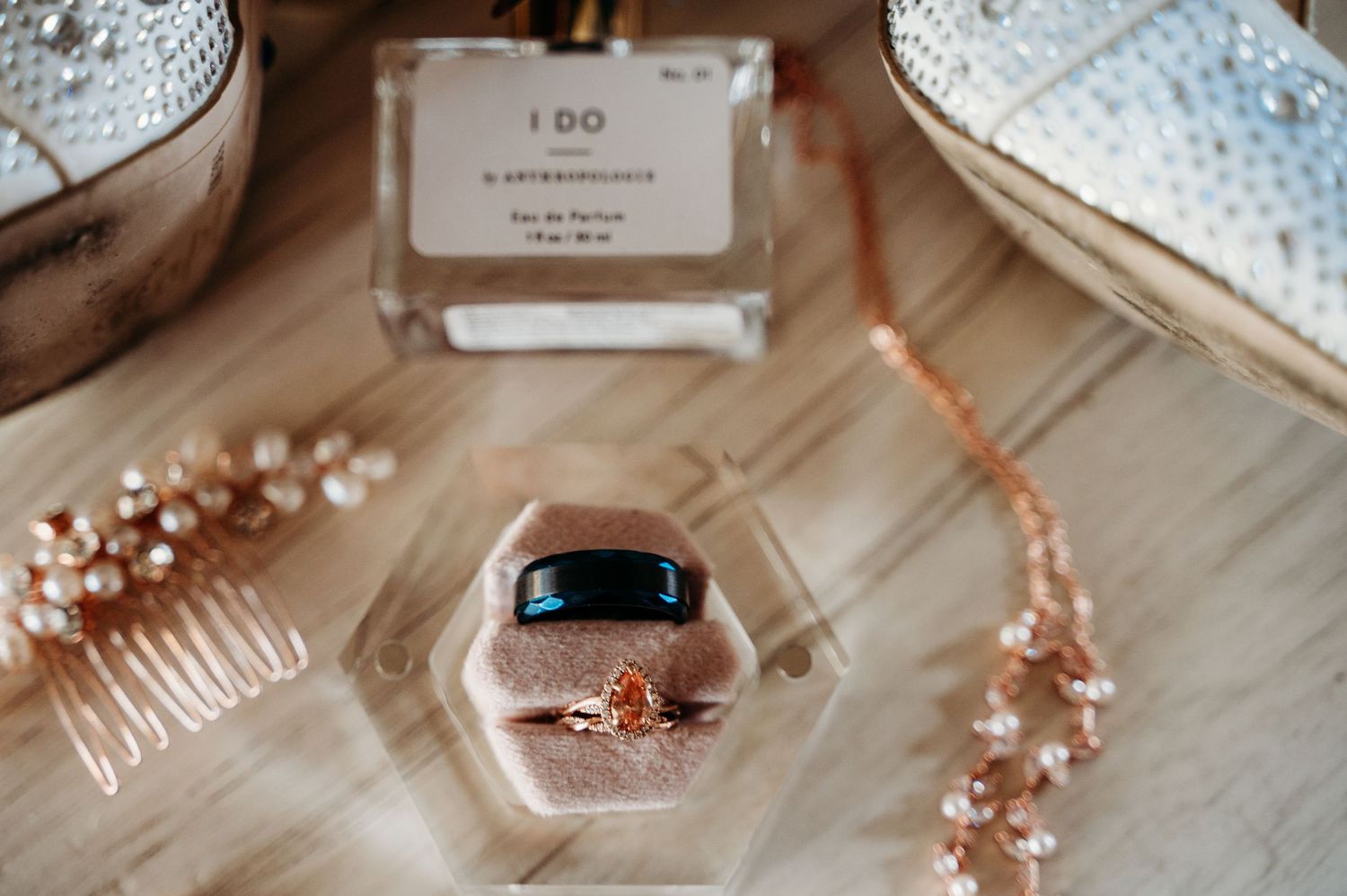 Wedding accessories including engagement ring, hair comb and pearl hairpiece arranged on a white surface.