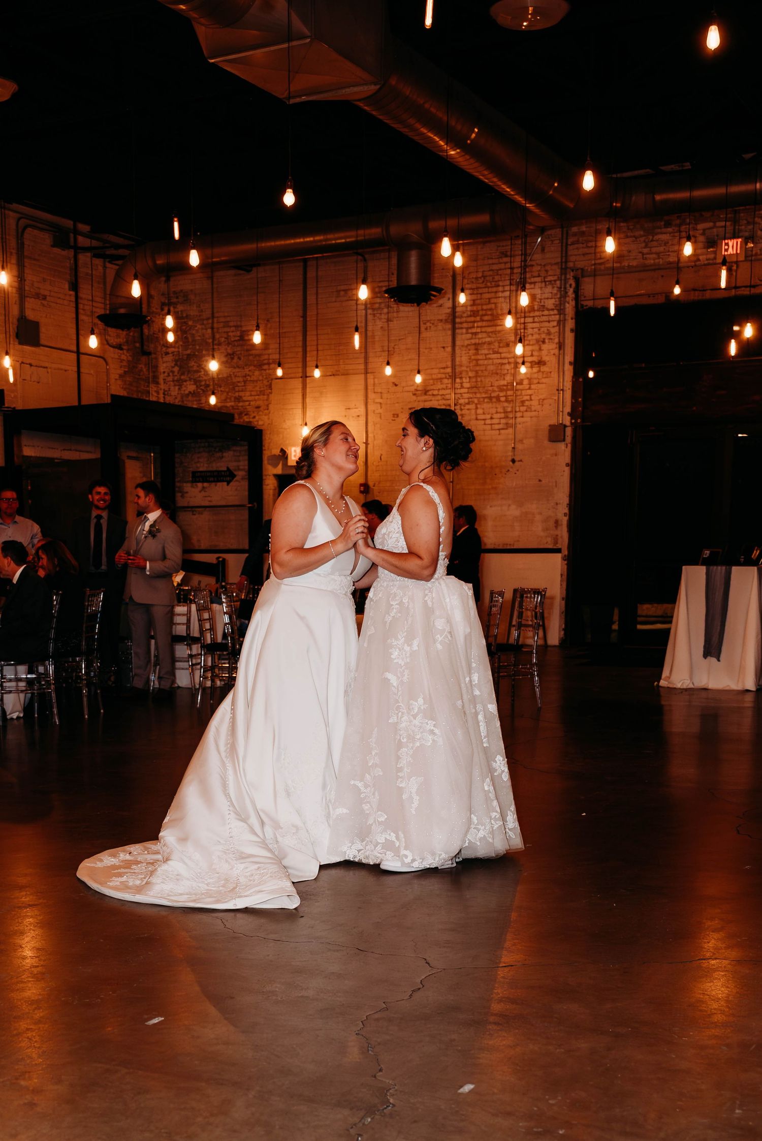 Wedding celebration in an industrial venue with string lights and exposed brick walls.