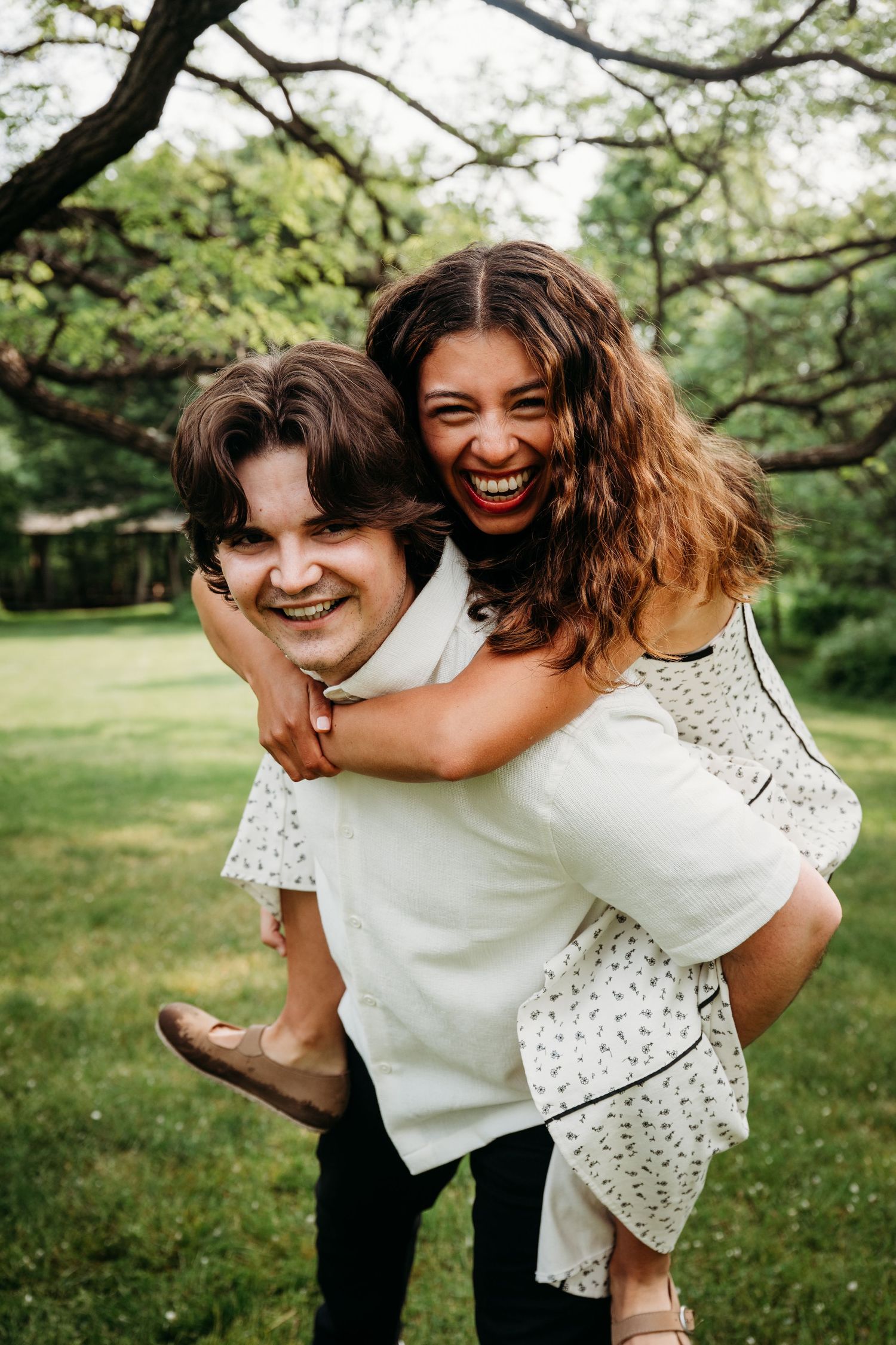 A playful piggyback ride moment captured in a green garden setting with bright summer sunshine.