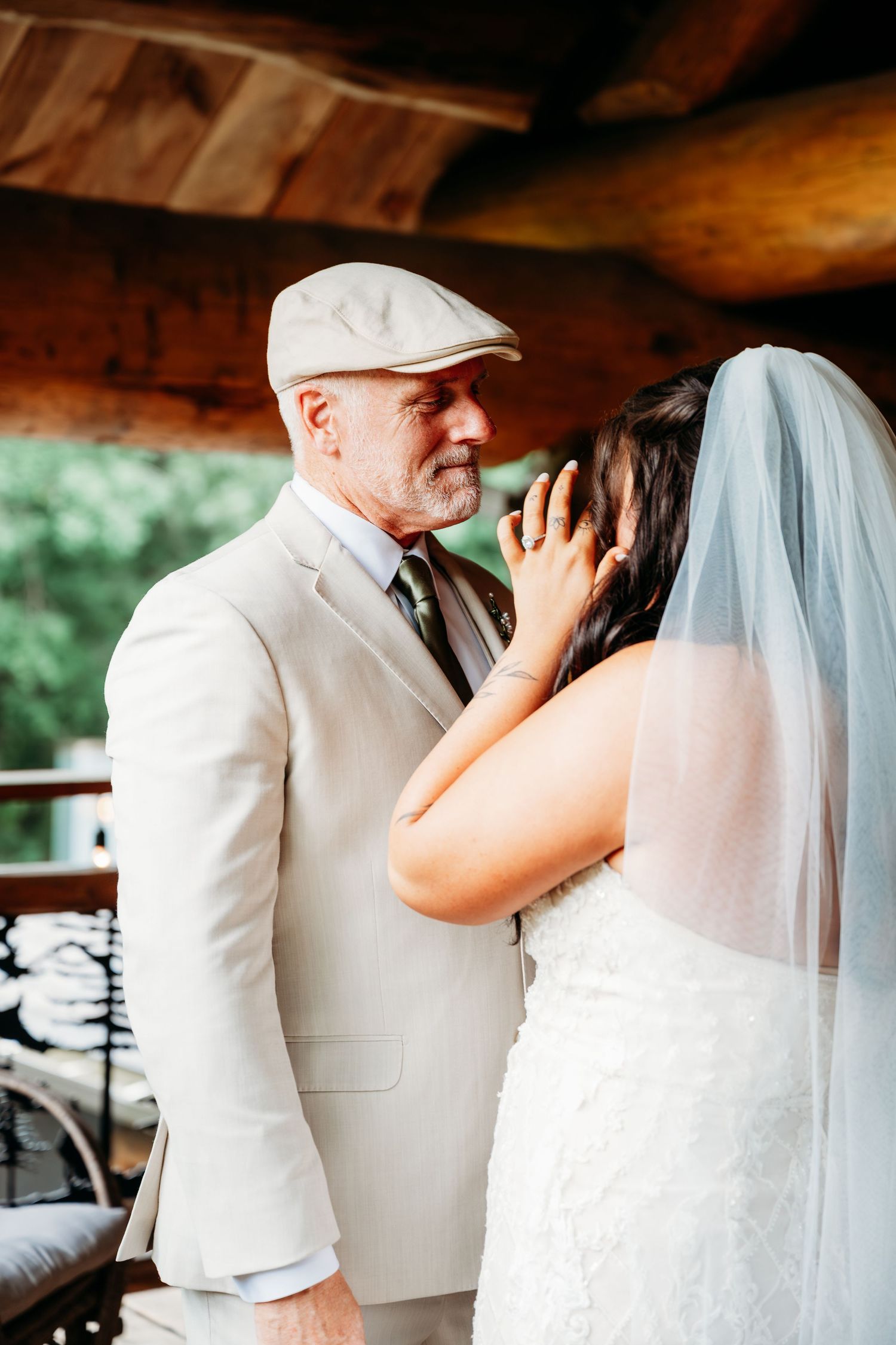 Emotional father-daughter first look moment at a wedding, with the father tenderly cupping his daughters face.