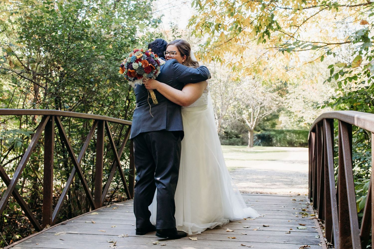 A couple shares a romantic moment on a rustic wooden bridge in a lush garden setting.