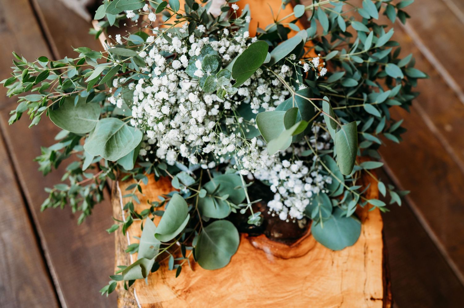 Fresh eucalyptus and baby's breath floral arrangement in wooden box on rustic table.