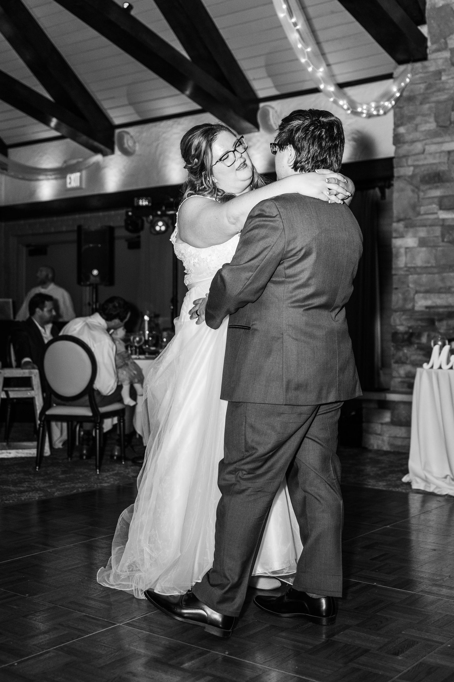 A black and white photo capturing an intimate first dance moment at a wedding reception.