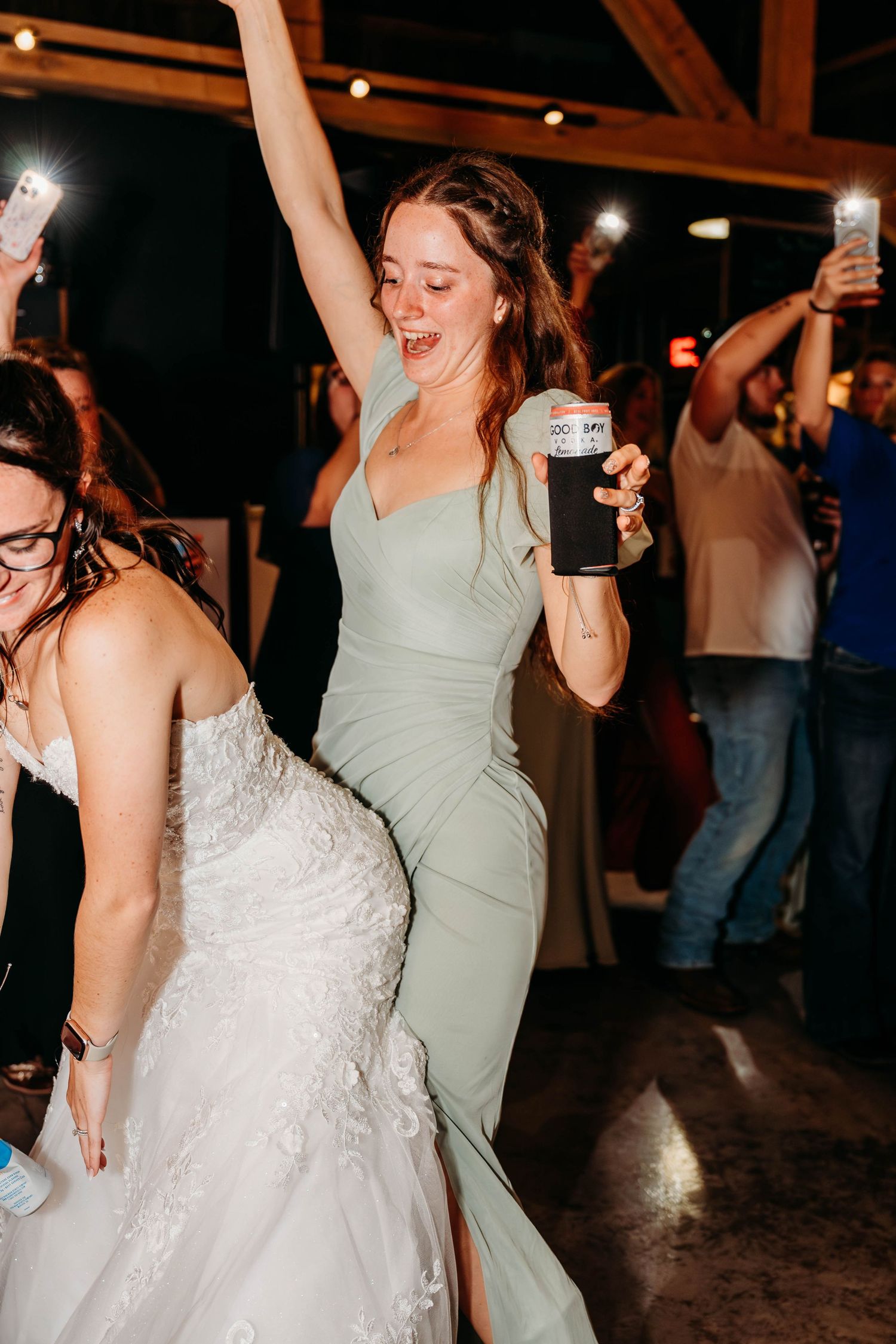 Wedding party dancing and celebrating at a dimly lit reception venue.