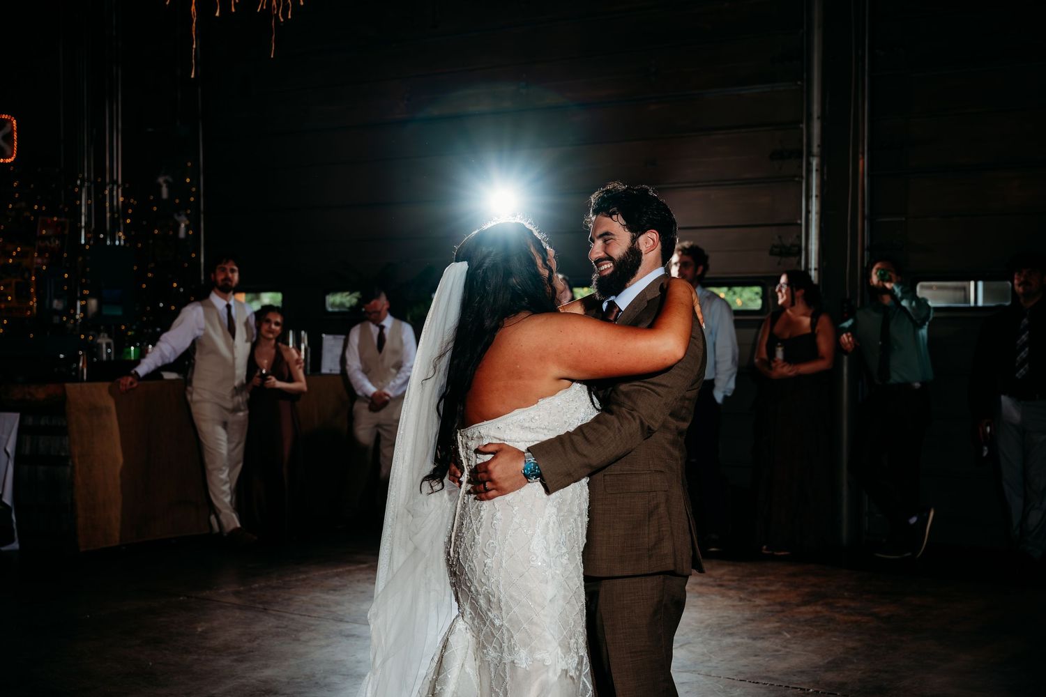 Bride and groom share their first dance at a romantic wedding reception in a dimly lit venue.