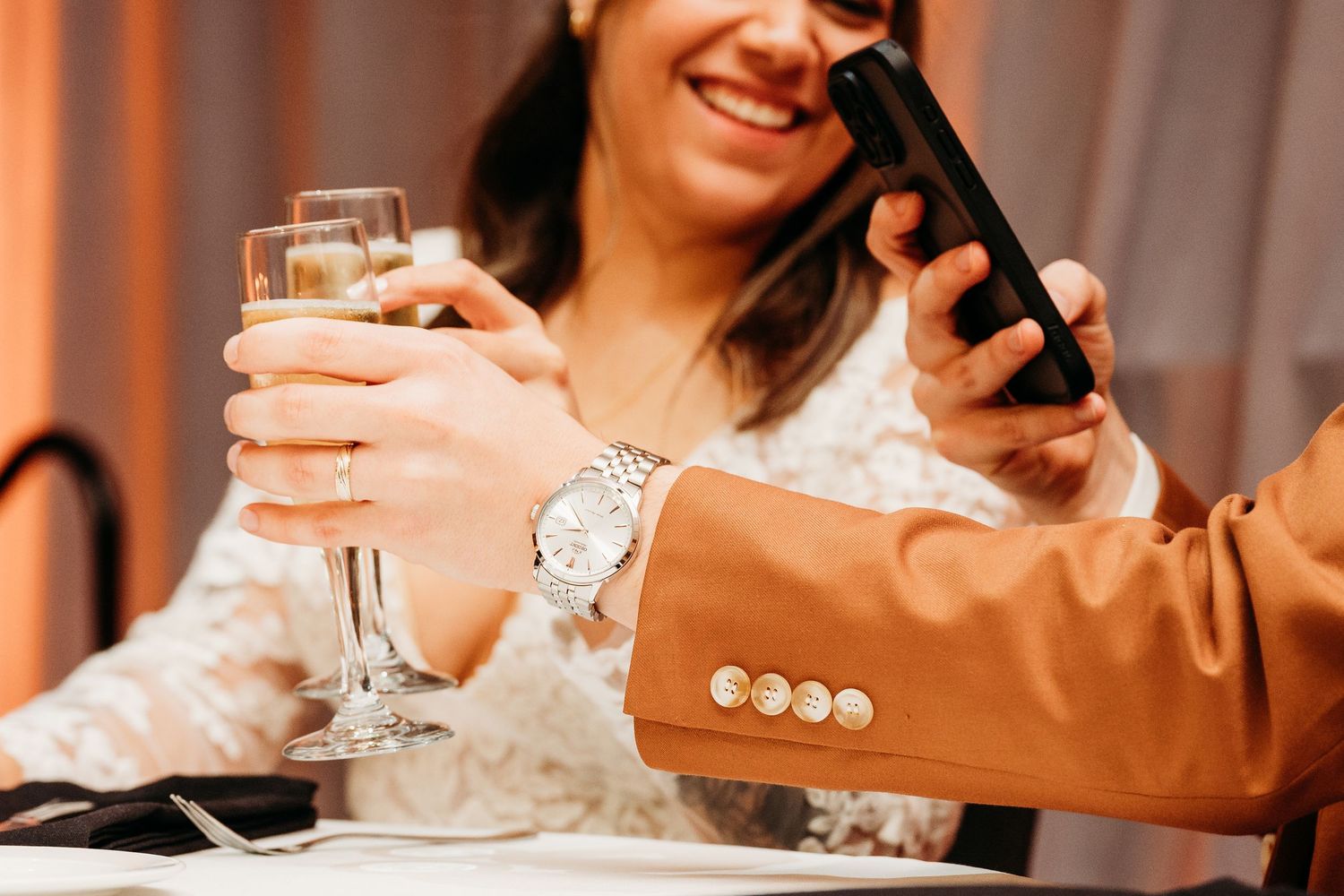 Wedding guests raise glasses in a toast during an elegant indoor reception celebration.